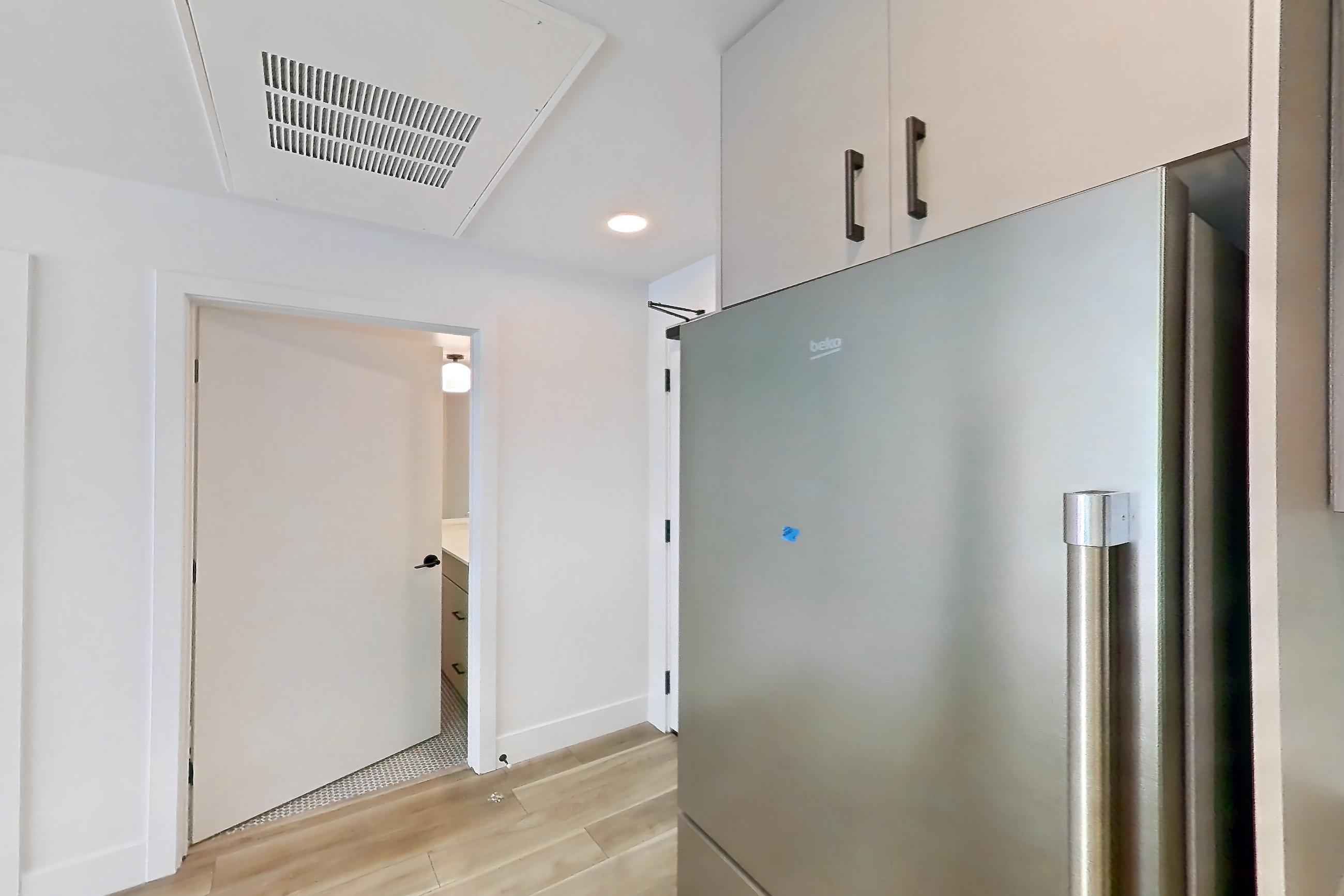 Kitchen with dishwasher, gas range, light countertops, light wood-finish flooring, oven/range, refrigerator, and stainless steel appliances, Apartment 403 at The Myles
