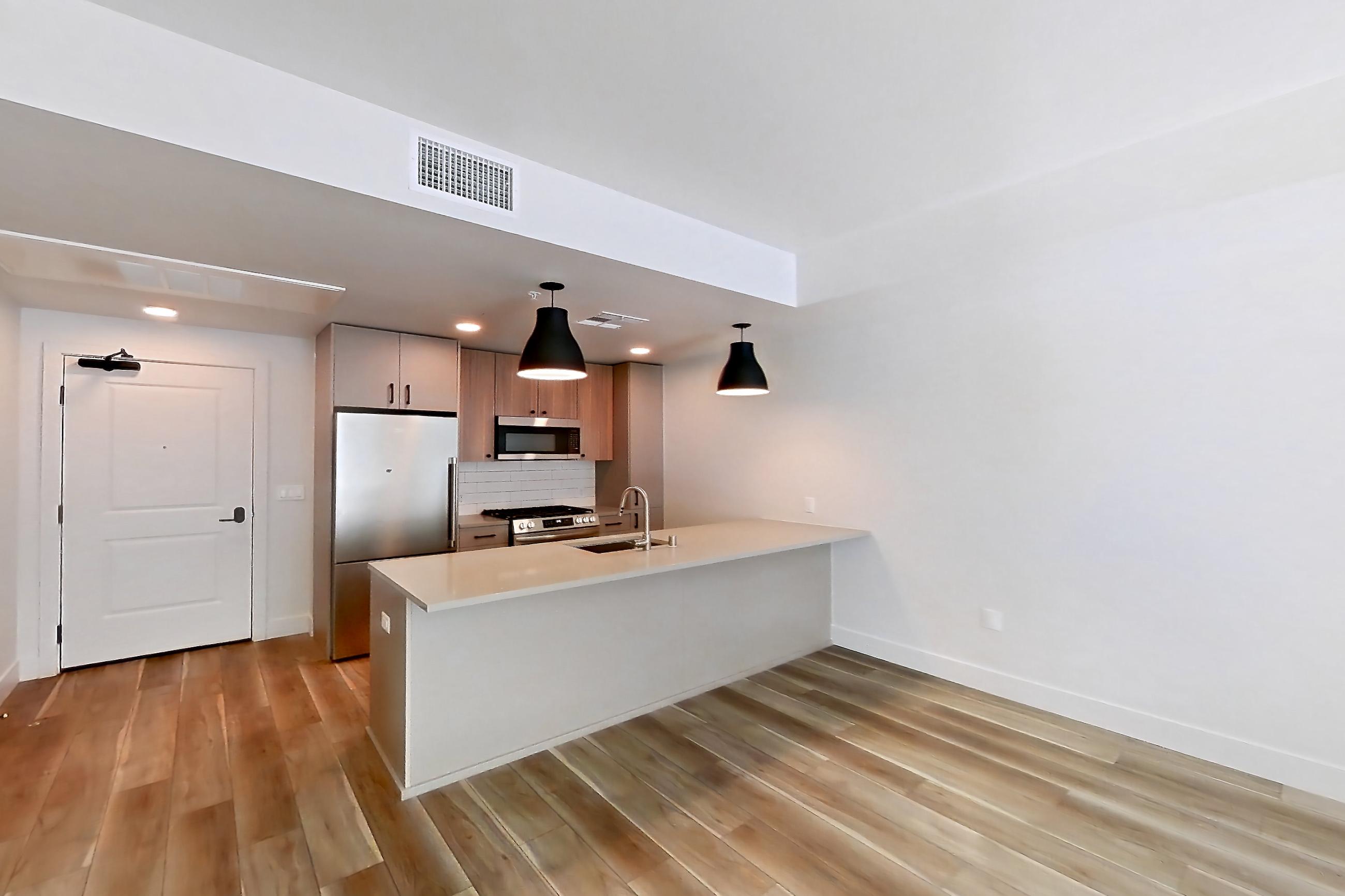 Living room with gas range, light countertops, light wood-finish flooring, oven/range, and stainless steel appliances, Apartment 403 at The Myles