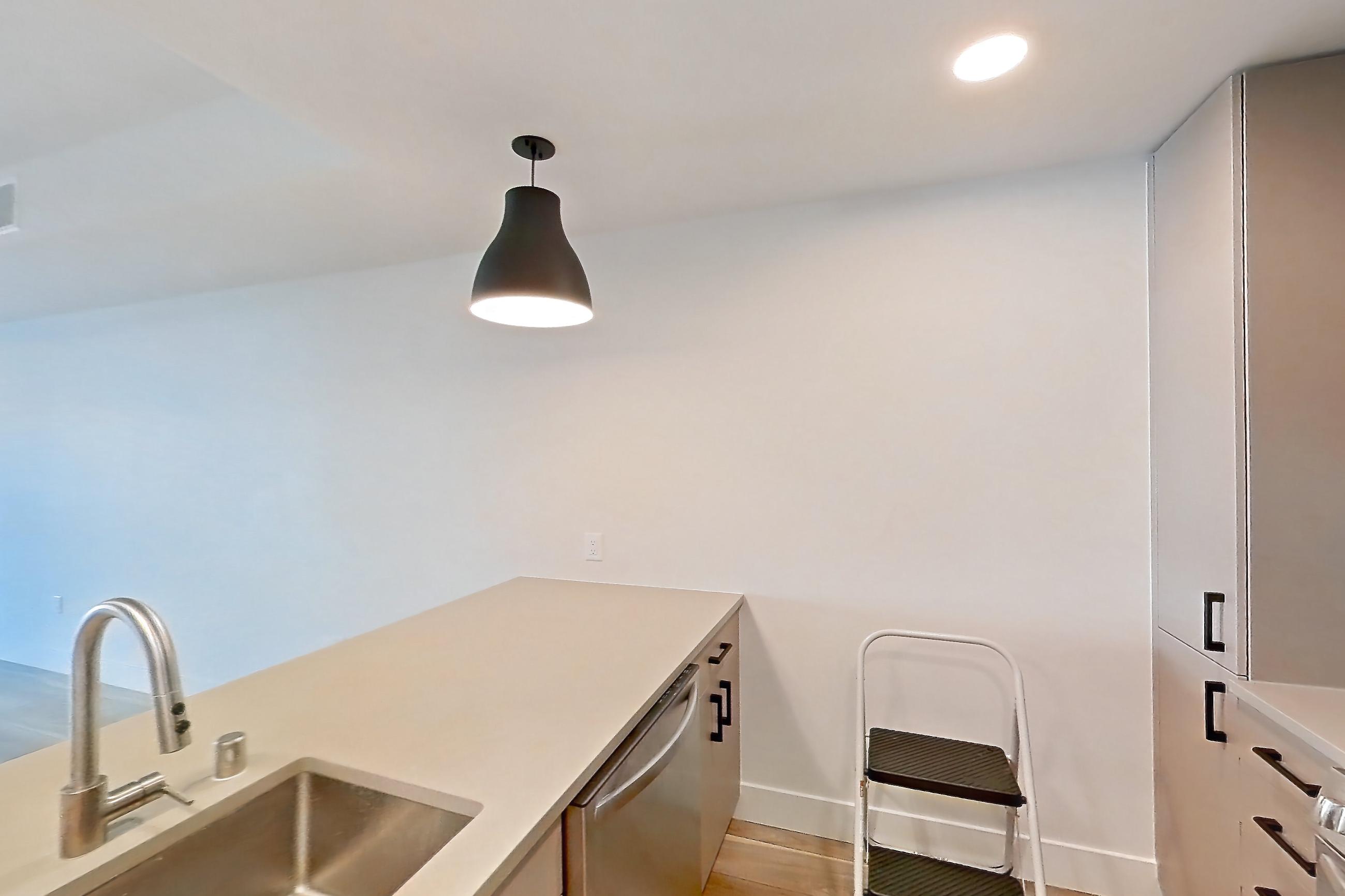 Kitchen with dishwasher, gas range, light countertops, light wood-finish flooring, microwave, oven/range, refrigerator, and stainless steel appliances, Apartment 404 at The Myles