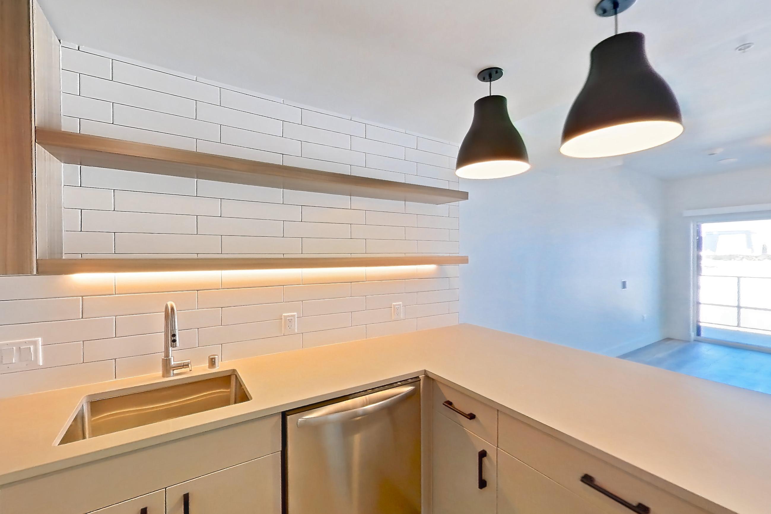 Kitchen with dishwasher, gas range, light countertops, light wood-finish flooring, microwave, oven/range, refrigerator, and stainless steel appliances, Apartment 409 at The Myles