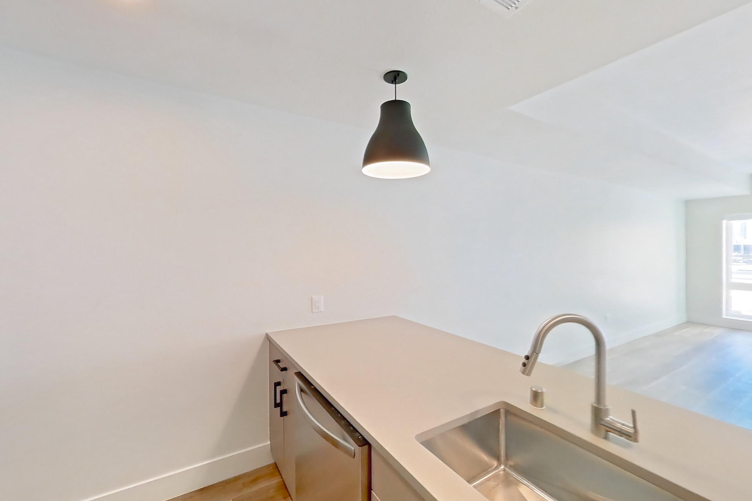 Kitchen with dishwasher, gas range, light countertops, light wood-finish flooring, oven/range, refrigerator, and stainless steel appliances, Apartment 411 at The Myles