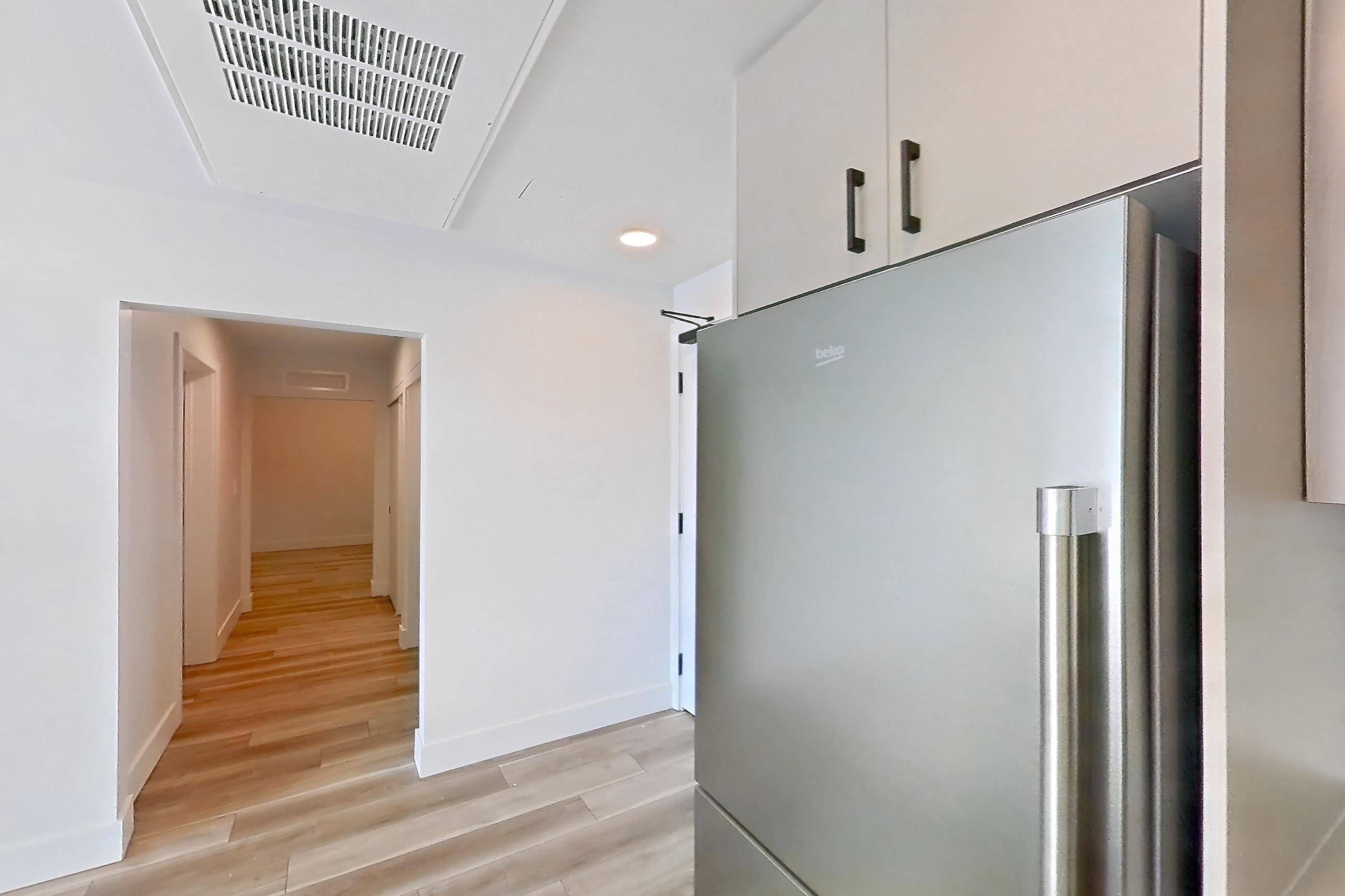 Kitchen with dishwasher, gas range, light countertops, light wood-finish flooring, oven/range, refrigerator, and stainless steel appliances, Apartment 411 at The Myles