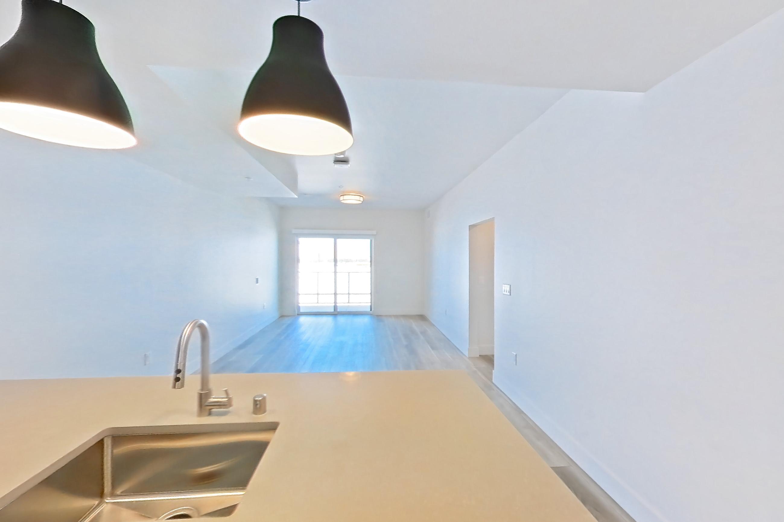 Kitchen with dishwasher, gas range, light countertops, light stone countertops, light wood-finish flooring, oven/range, refrigerator, and stainless steel appliances, Apartment 412 at The Myles