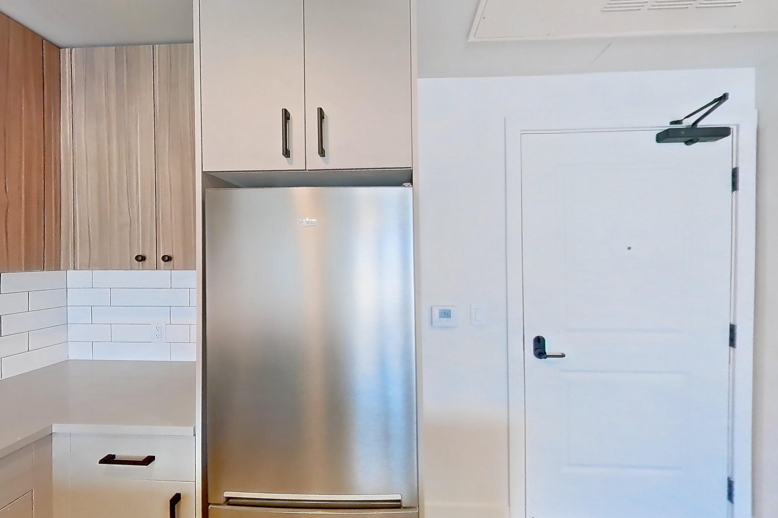 Kitchen with gas range, light countertops, light stone countertops, light wood-finish flooring, oven/range, refrigerator, stainless steel appliances, and wood-look tile flooring, Apartment 413 at The Myles