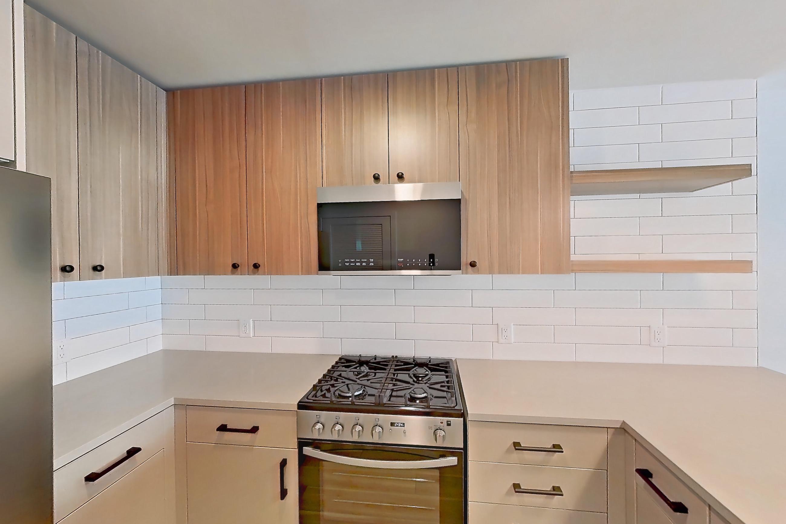 Kitchen with gas range, light countertops, light wood-finish flooring, oven/range, refrigerator, and stainless steel appliances, Apartment 435 at The Myles