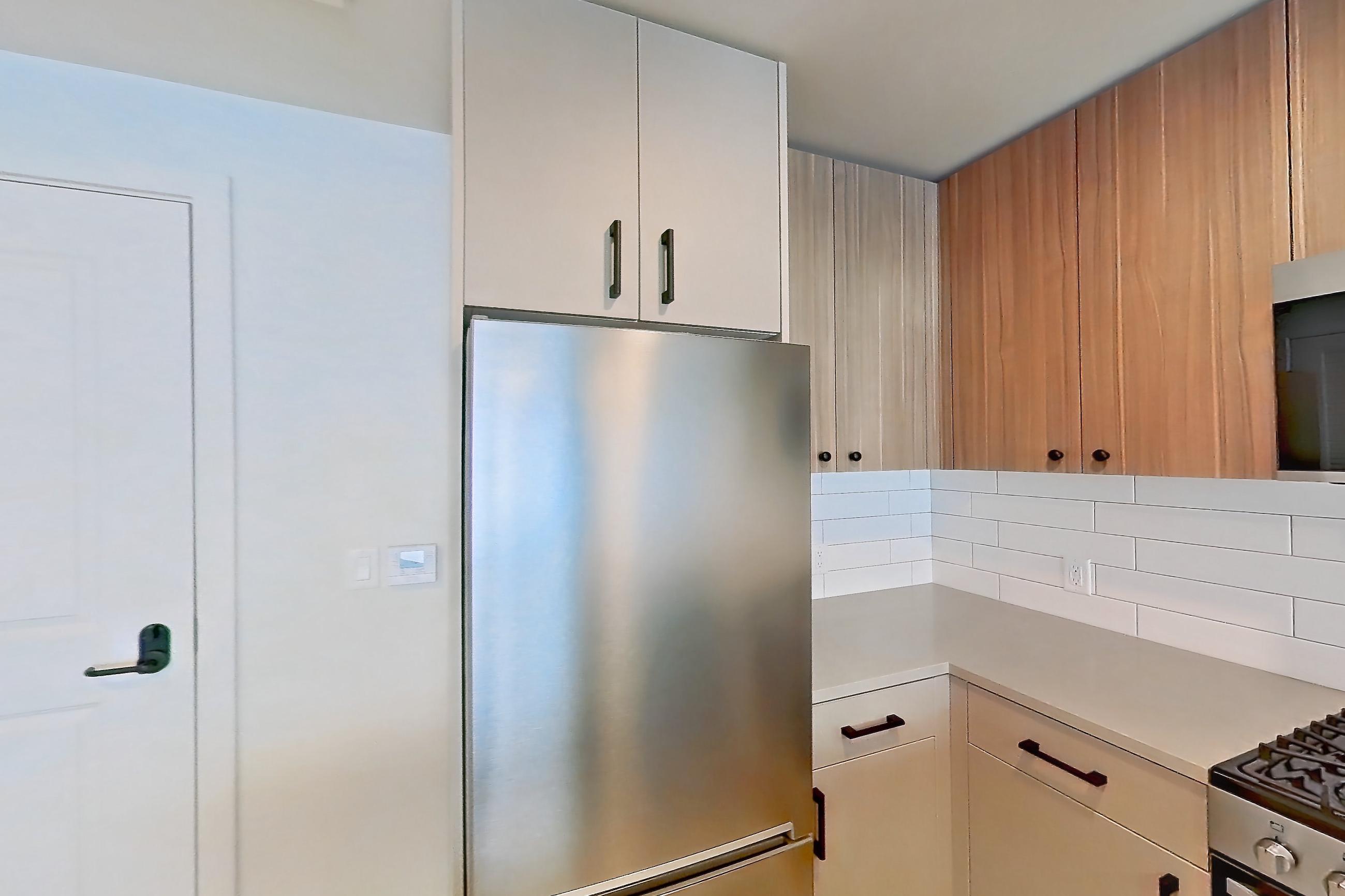 Kitchen with gas range, light countertops, light wood-finish flooring, oven/range, refrigerator, and stainless steel appliances, Apartment 435 at The Myles