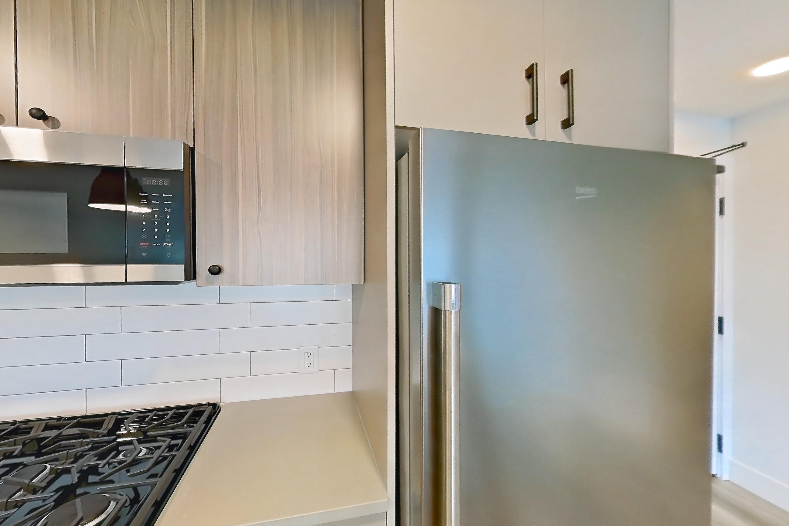 Kitchen with dishwasher, gas range, light countertops, light wood-finish flooring, oven/range, refrigerator, and stainless steel appliances, Apartment 436 at The Myles