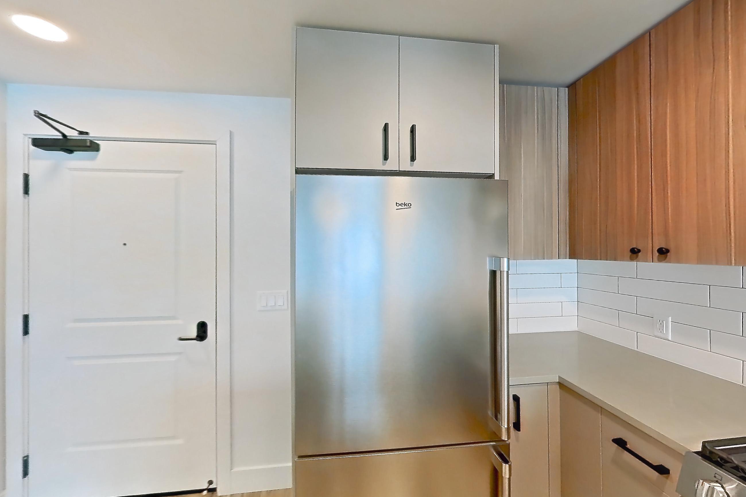 Kitchen with dishwasher, gas range, light countertops, light wood-finish flooring, microwave, oven/range, refrigerator, and stainless steel appliances, Apartment 437 at The Myles