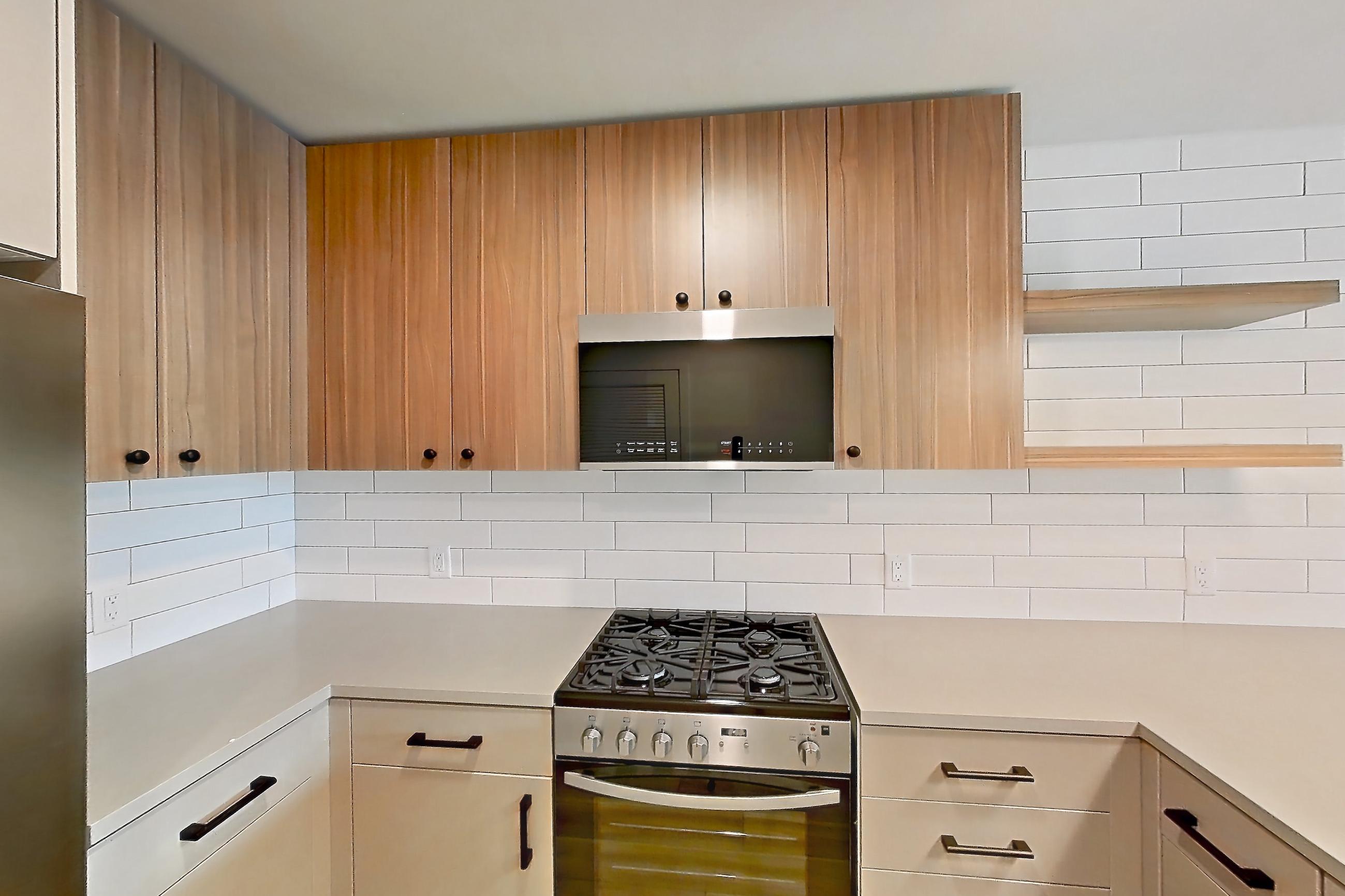 Kitchen with dishwasher, gas range, light countertops, light wood-finish flooring, oven/range, refrigerator, and stainless steel appliances, Apartment 438 at The Myles