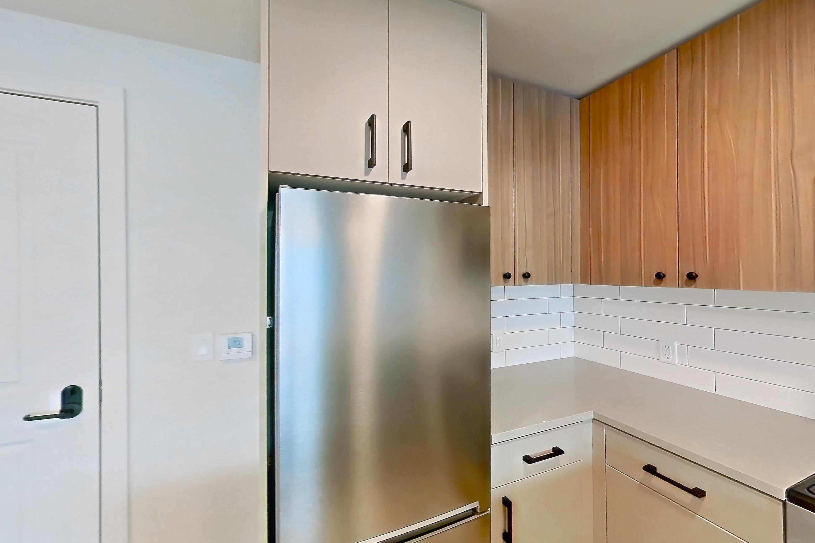Kitchen with dishwasher, gas range, light countertops, light wood-finish flooring, oven/range, refrigerator, and stainless steel appliances, Apartment 438 at The Myles