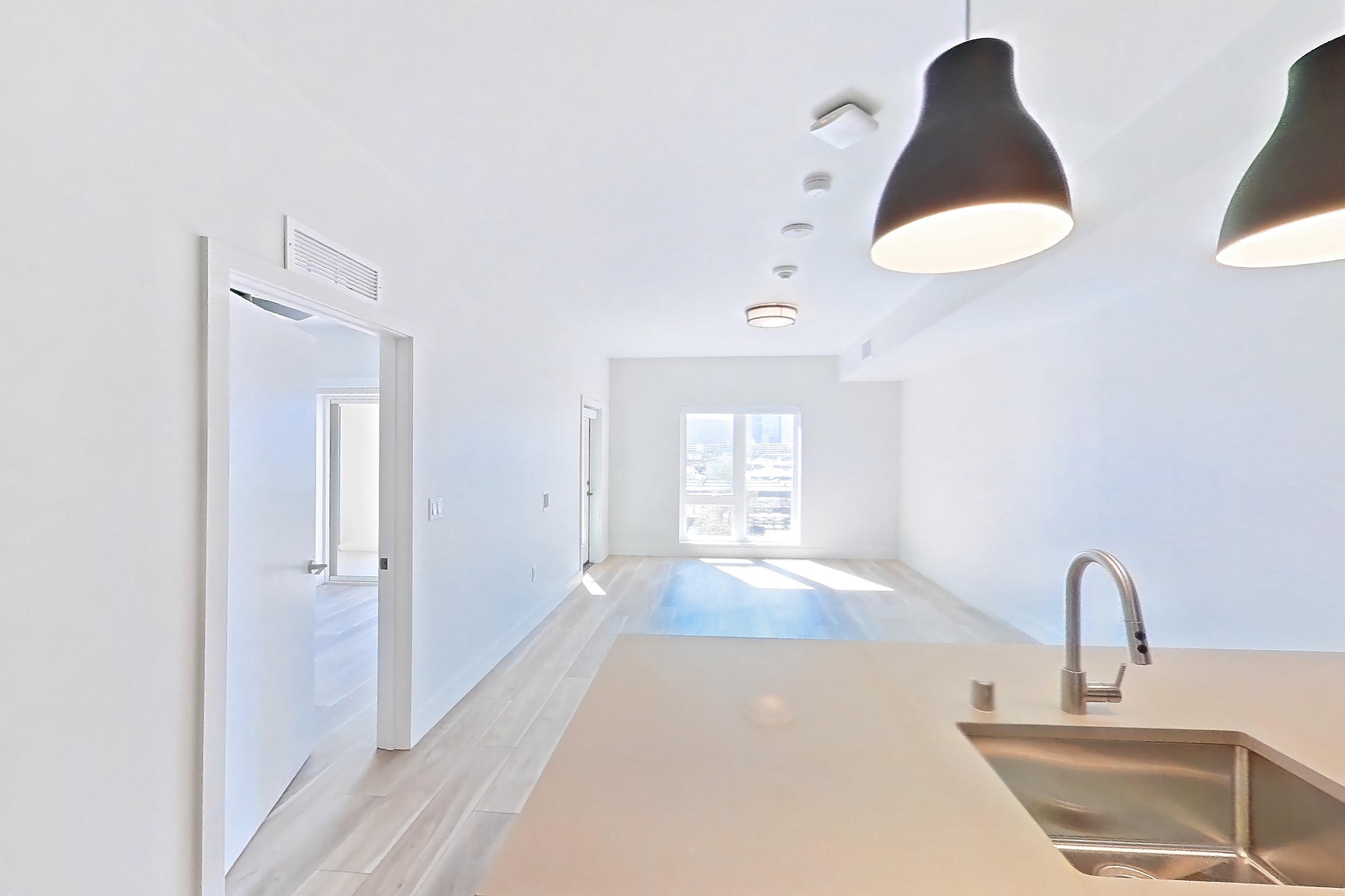 Kitchen with dishwasher, gas range, light countertops, light wood-finish flooring, microwave, oven/range, refrigerator, and stainless steel appliances, Apartment 440 at The Myles