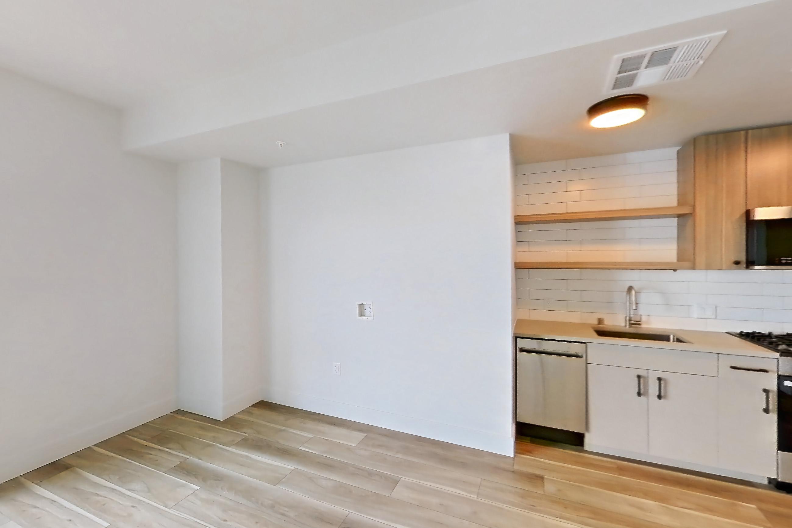 Living space with dishwasher, gas range, light countertops, light wood-finish flooring, oven/range, refrigerator, and stainless steel appliances, Apartment 443 at The Myles