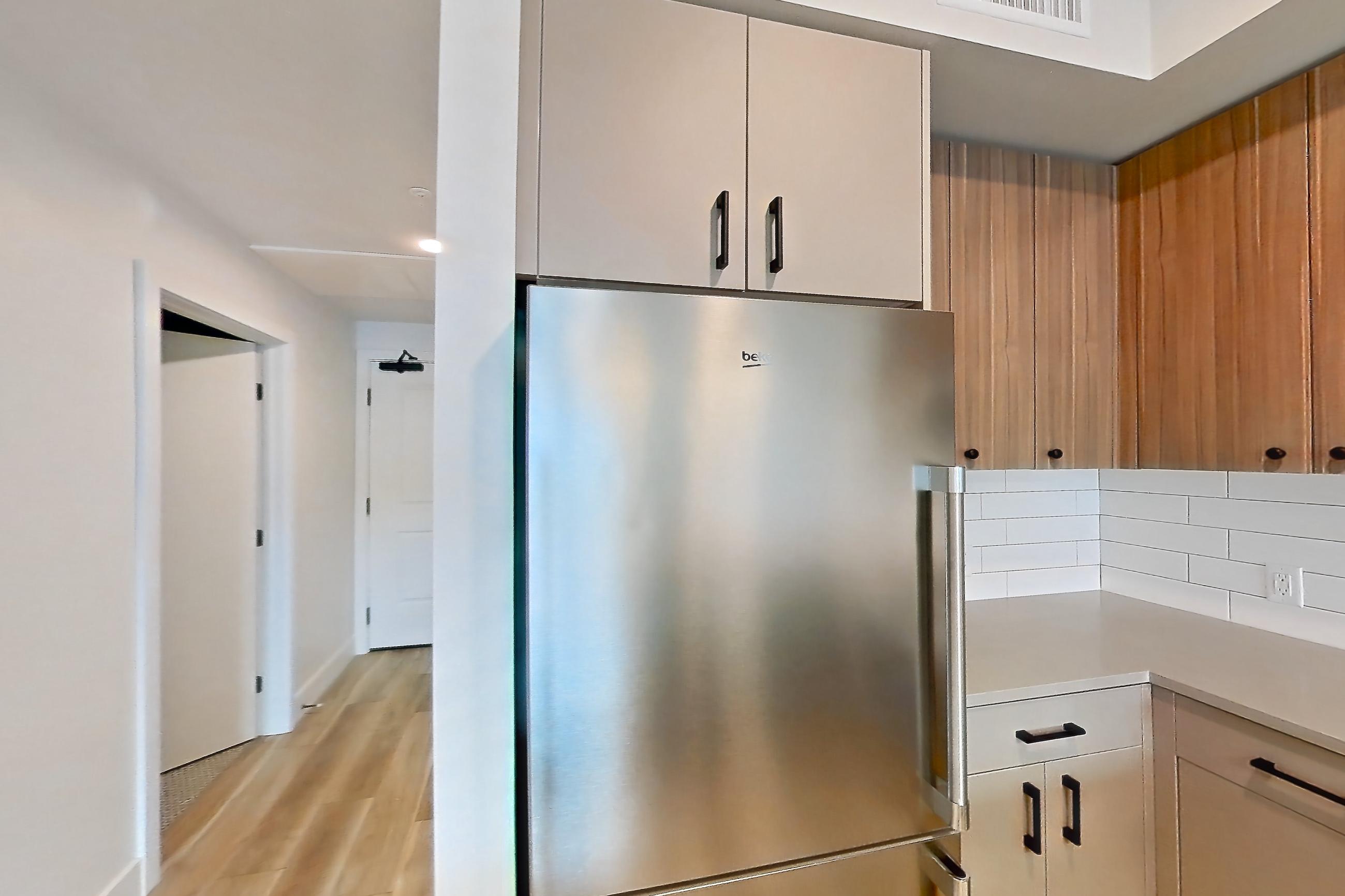 Kitchen with dishwasher, gas range, light countertops, light wood-finish flooring, microwave, oven/range, refrigerator, and stainless steel appliances, Apartment 442 at The Myles