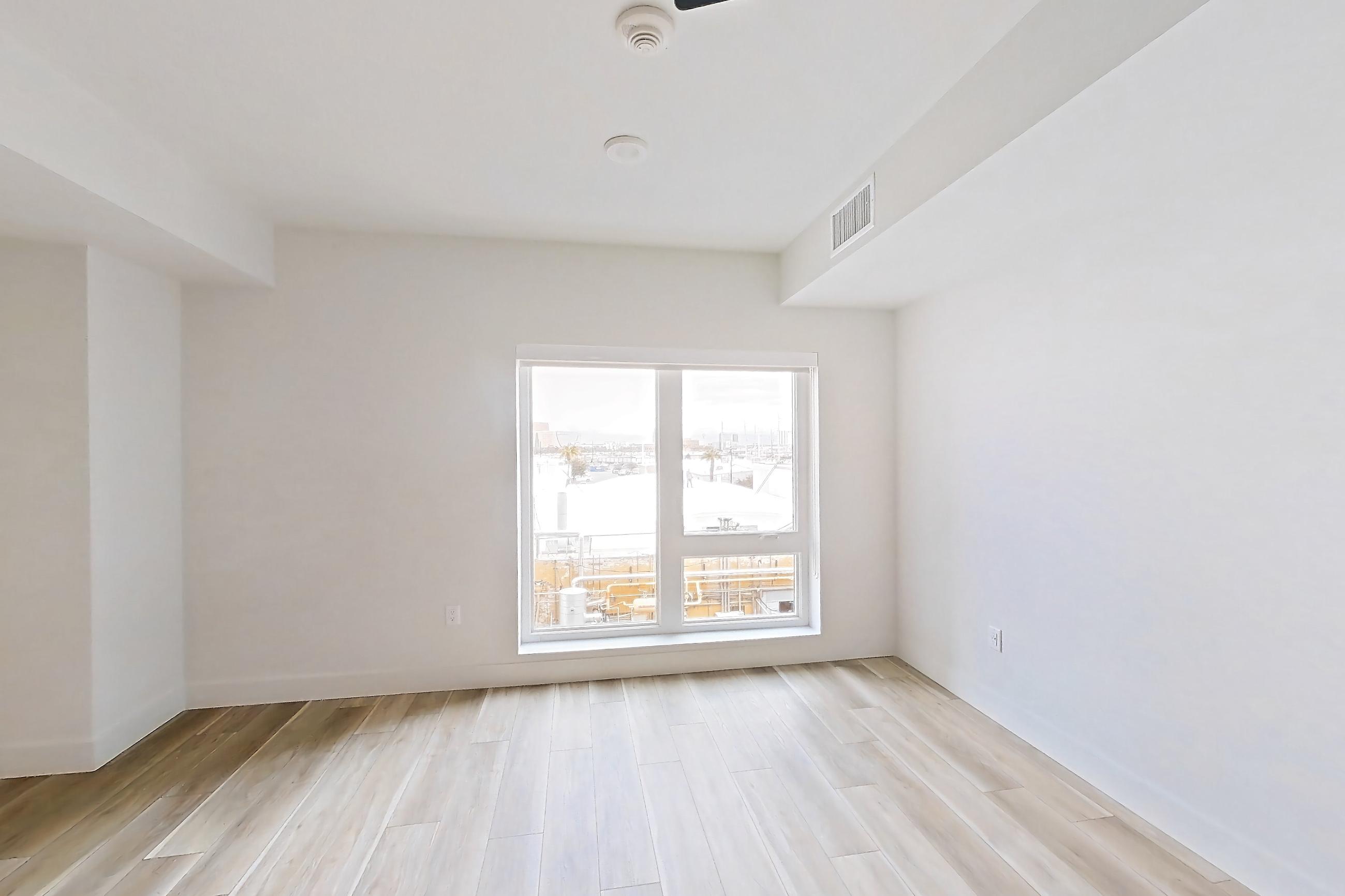 Living space with dishwasher, gas range, light stone countertops, light wood-finish flooring, oven/range, stainless steel appliances, and wood-look tile flooring, Apartment 445 at The Myles