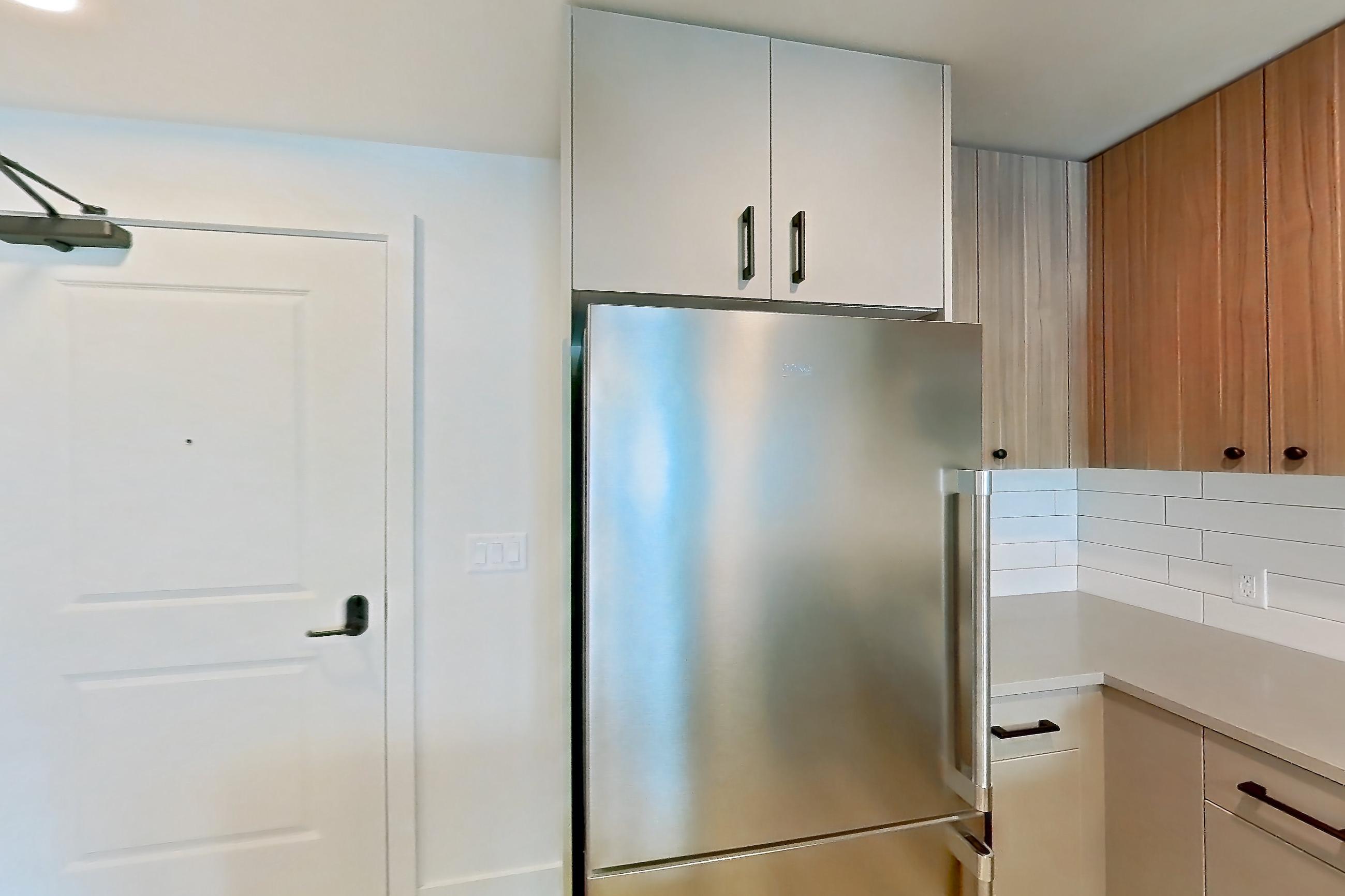 Kitchen with dishwasher, gas range, light countertops, light wood-finish flooring, microwave, oven/range, refrigerator, and stainless steel appliances, Apartment 447 at The Myles