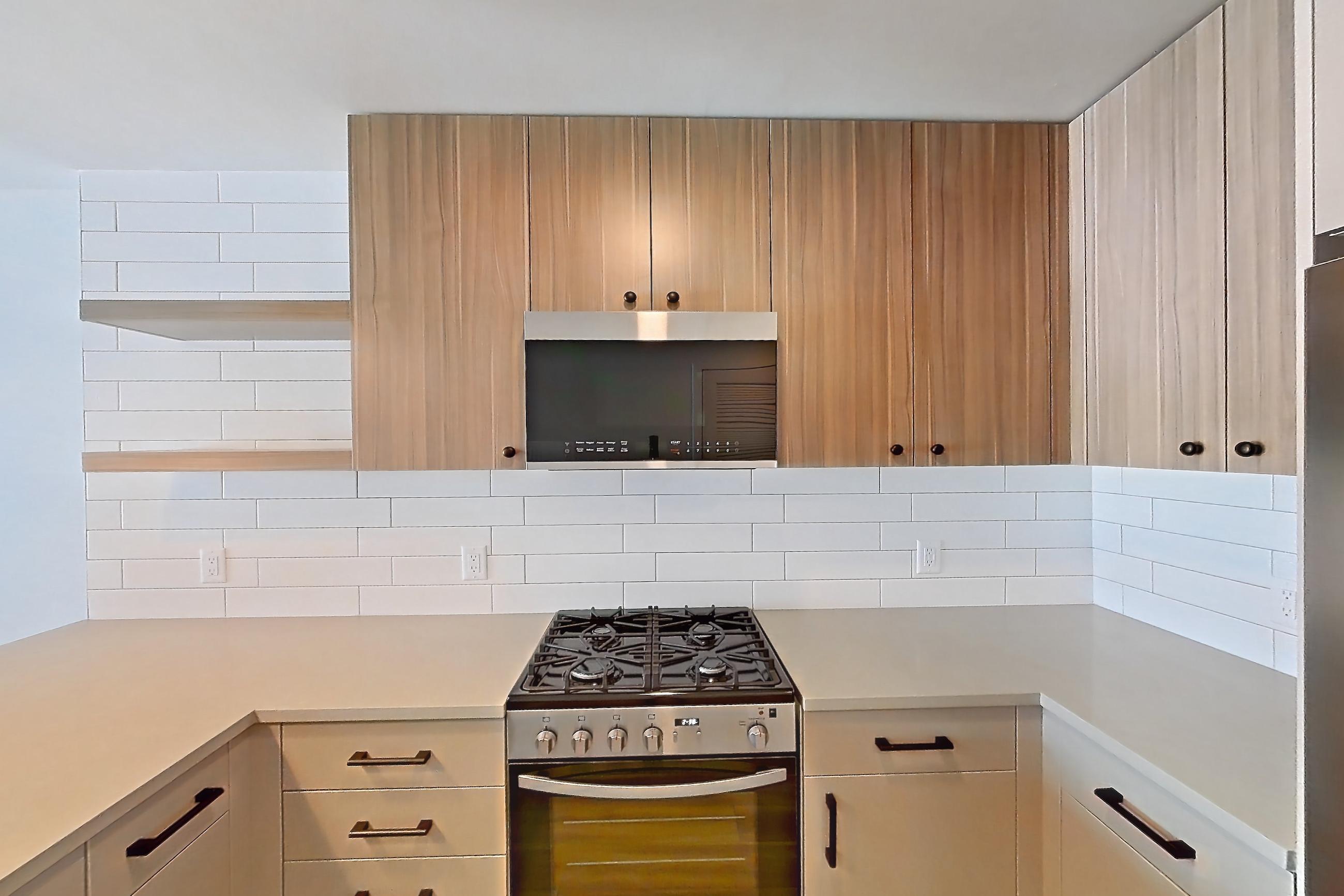 Kitchen with dishwasher, gas range, light countertops, light wood-finish flooring, oven/range, refrigerator, and stainless steel appliances, Apartment 510 at The Myles