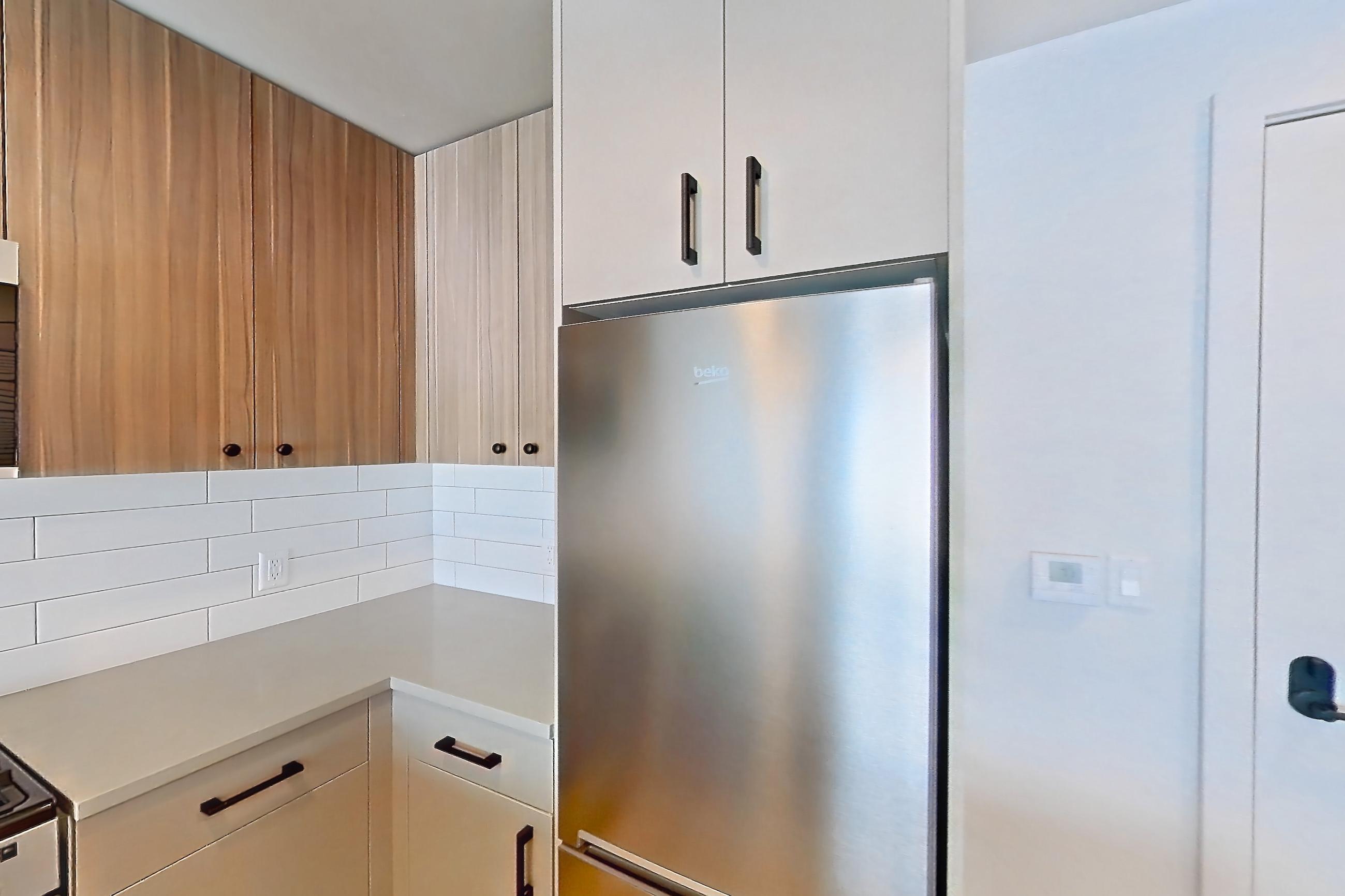 Kitchen with dishwasher, gas range, light countertops, light wood-finish flooring, oven/range, refrigerator, and stainless steel appliances, Apartment 510 at The Myles