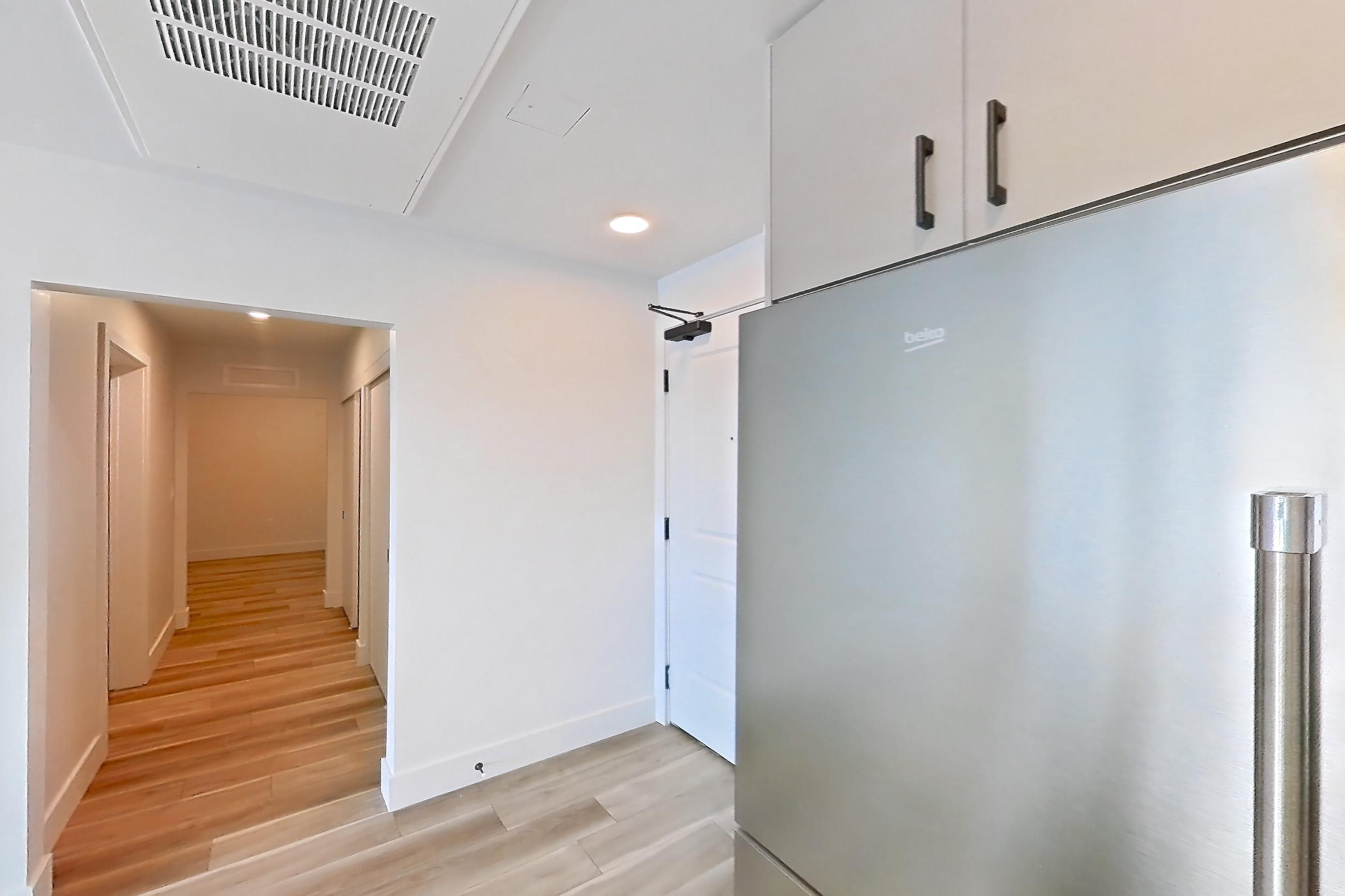 Kitchen with gas range, light countertops, light wood-finish flooring, oven/range, refrigerator, stainless steel appliances, and wood-look tile flooring, Apartment 511 at The Myles