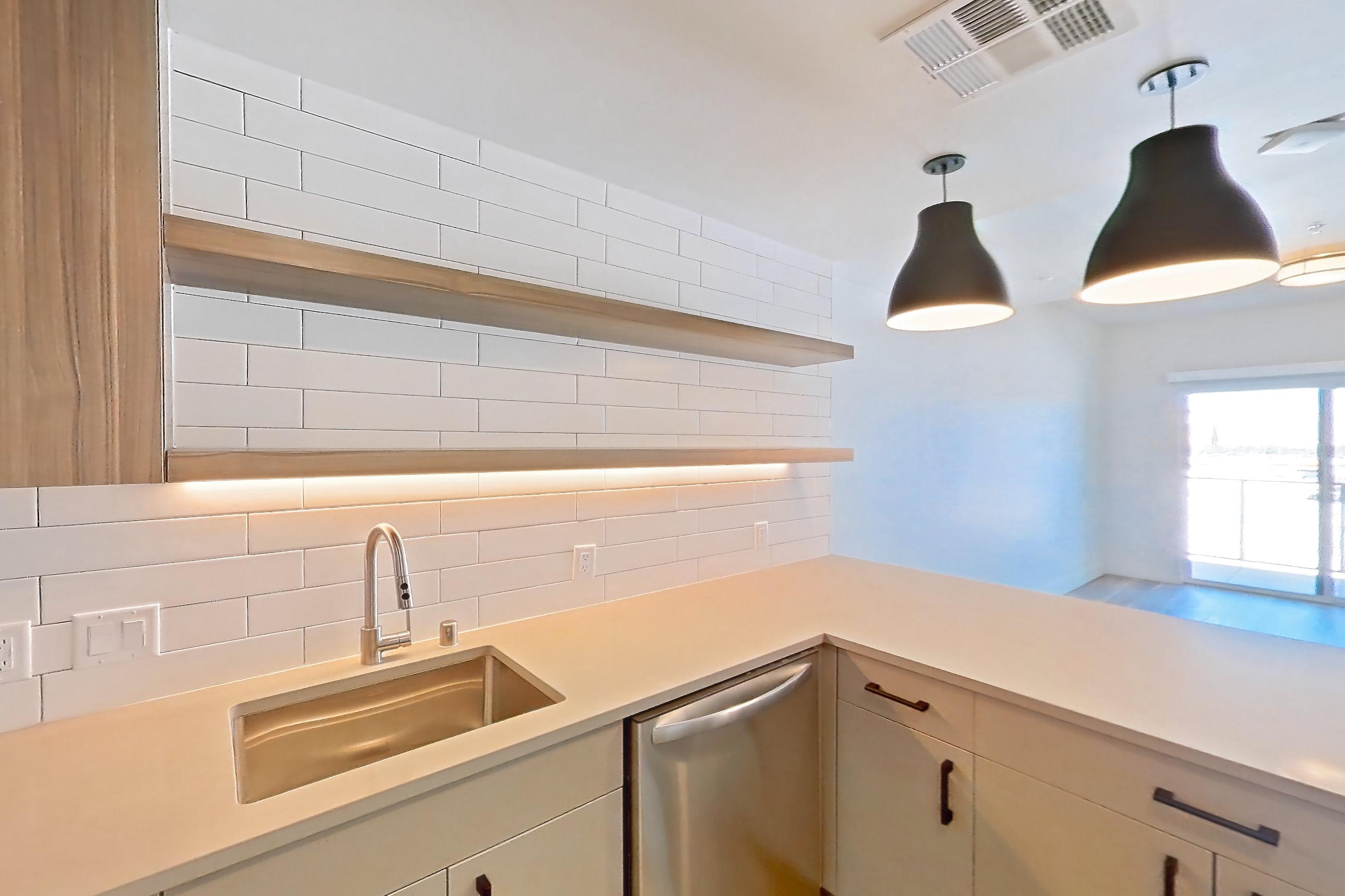 Kitchen with dishwasher, gas range, light countertops, light wood-finish flooring, microwave, oven/range, refrigerator, and stainless steel appliances, Apartment 516 at The Myles