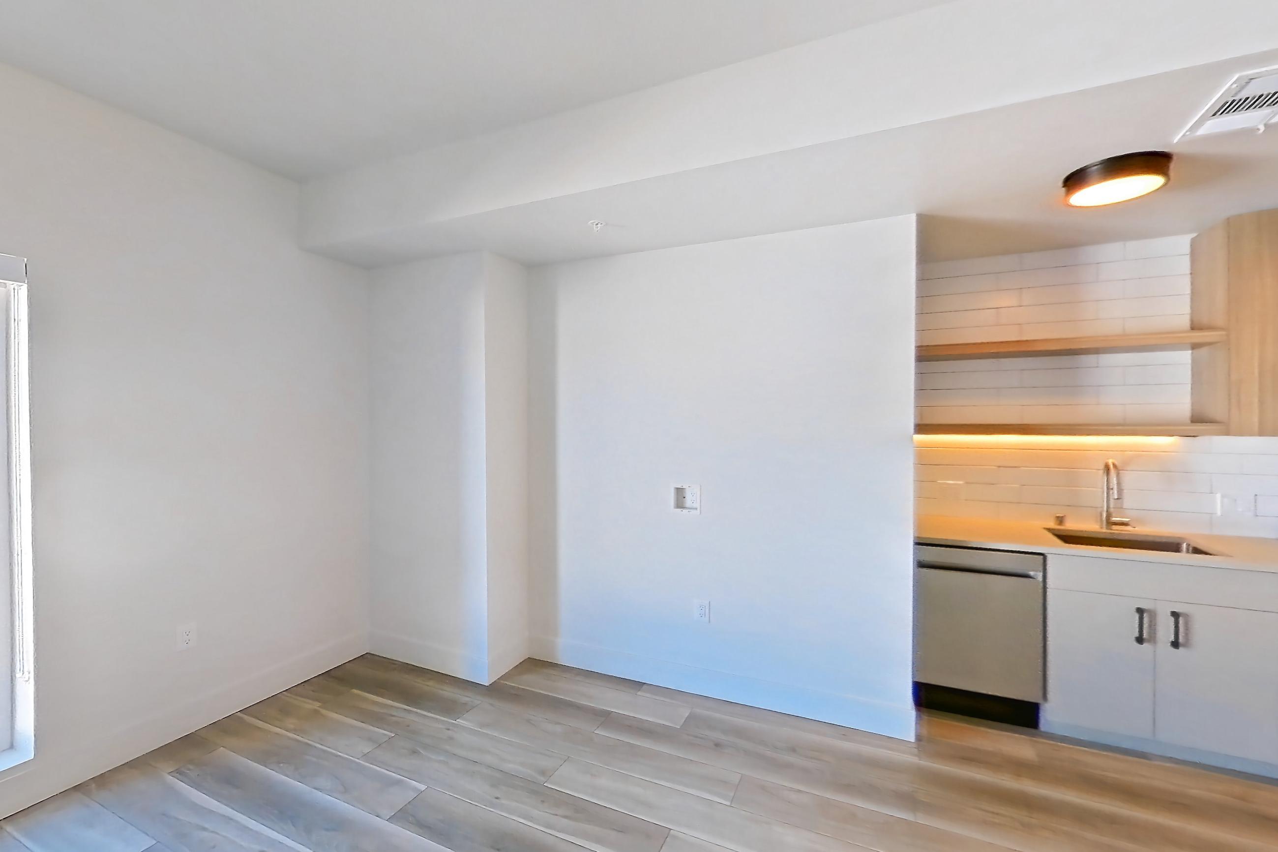 Living space with dishwasher, gas range, light countertops, light wood-finish flooring, oven/range, refrigerator, and stainless steel appliances, Apartment 520 at The Myles