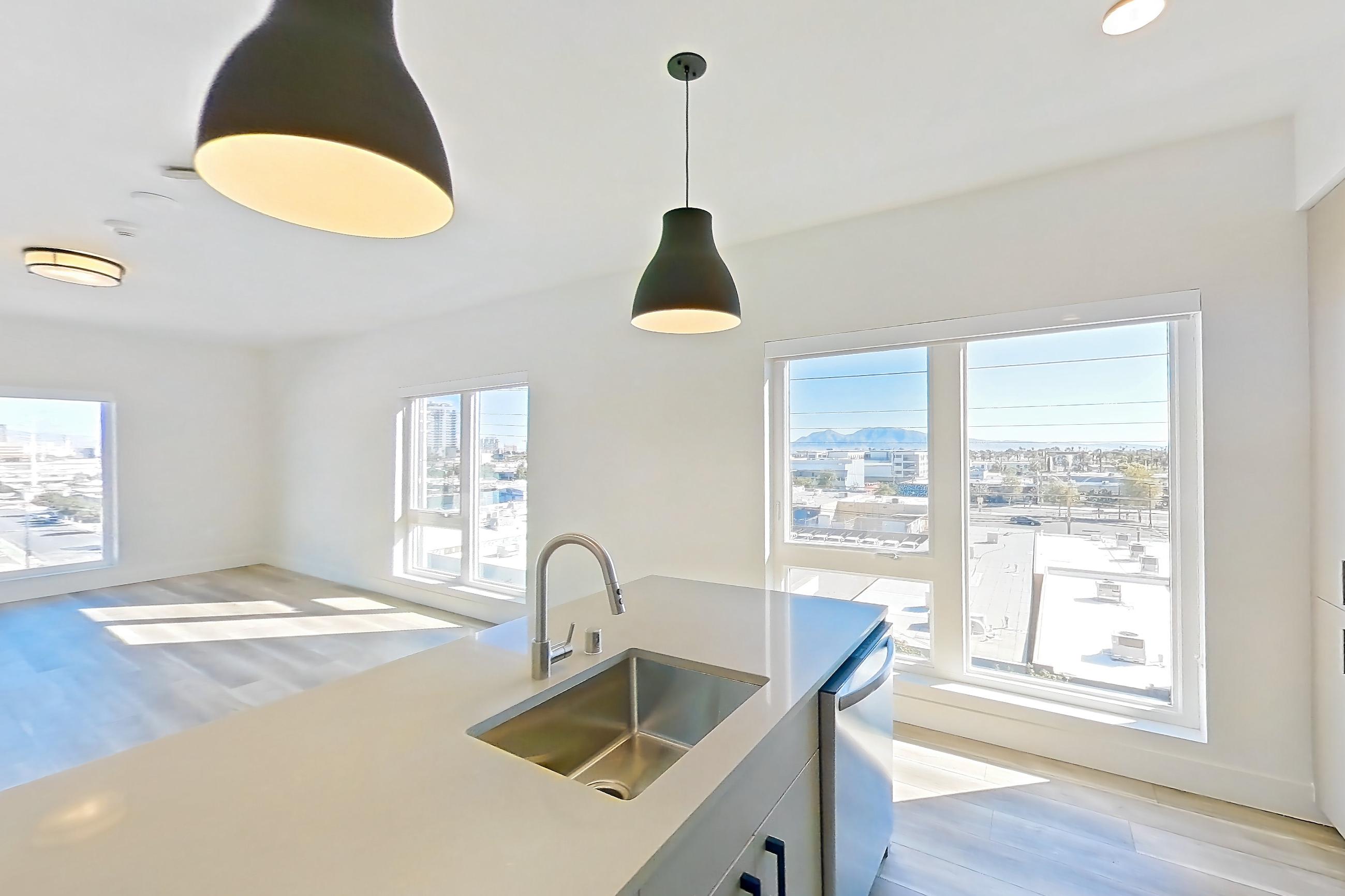 Kitchen with gas range, kitchen island, light countertops, light wood-finish flooring, microwave, oven/range, stainless steel appliances, and wood-look tile flooring, Apartment 524 at The Myles