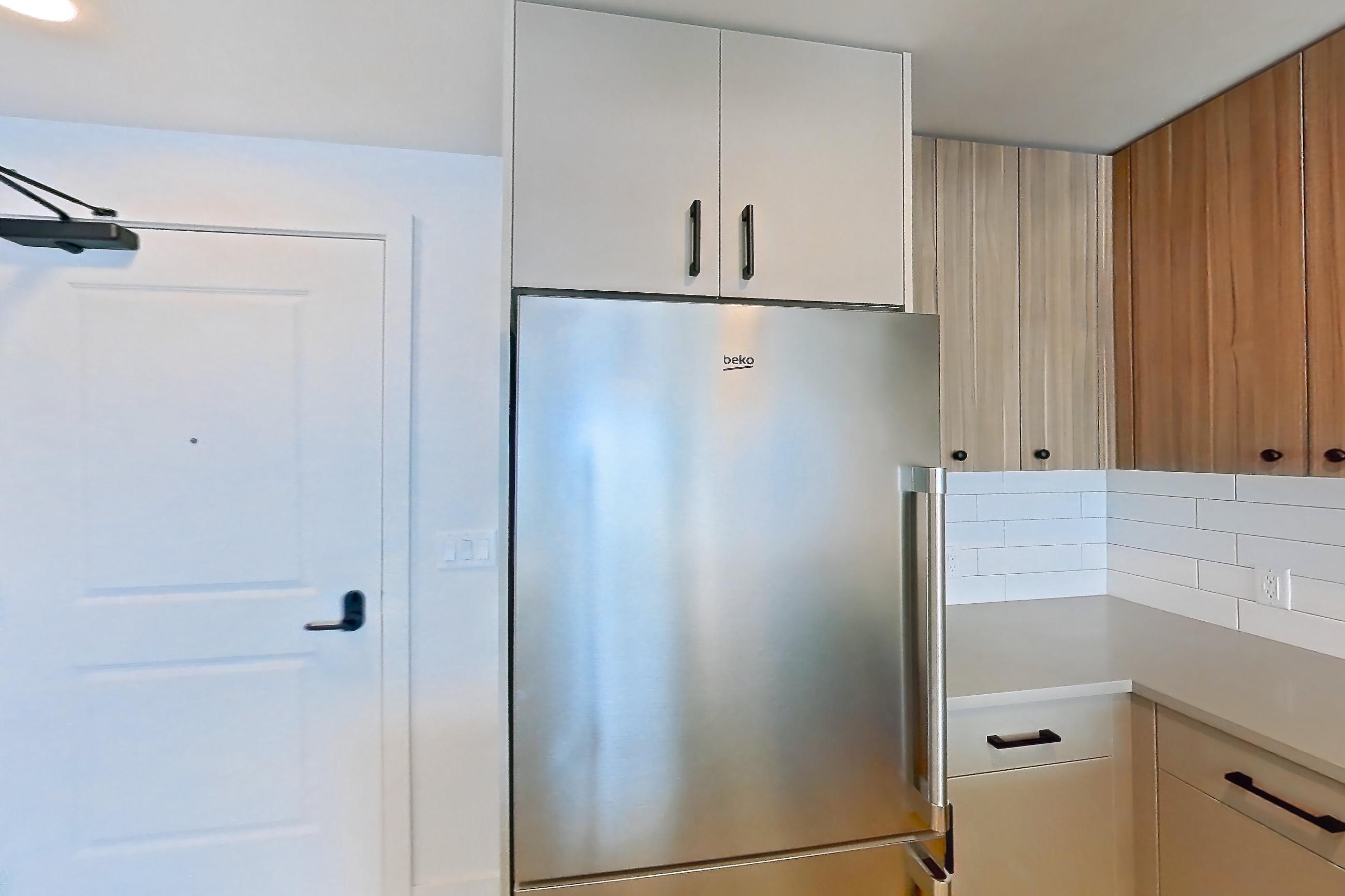 Kitchen with dishwasher, gas range, light countertops, light wood-finish flooring, microwave, oven/range, refrigerator, and stainless steel appliances, Apartment 525 at The Myles