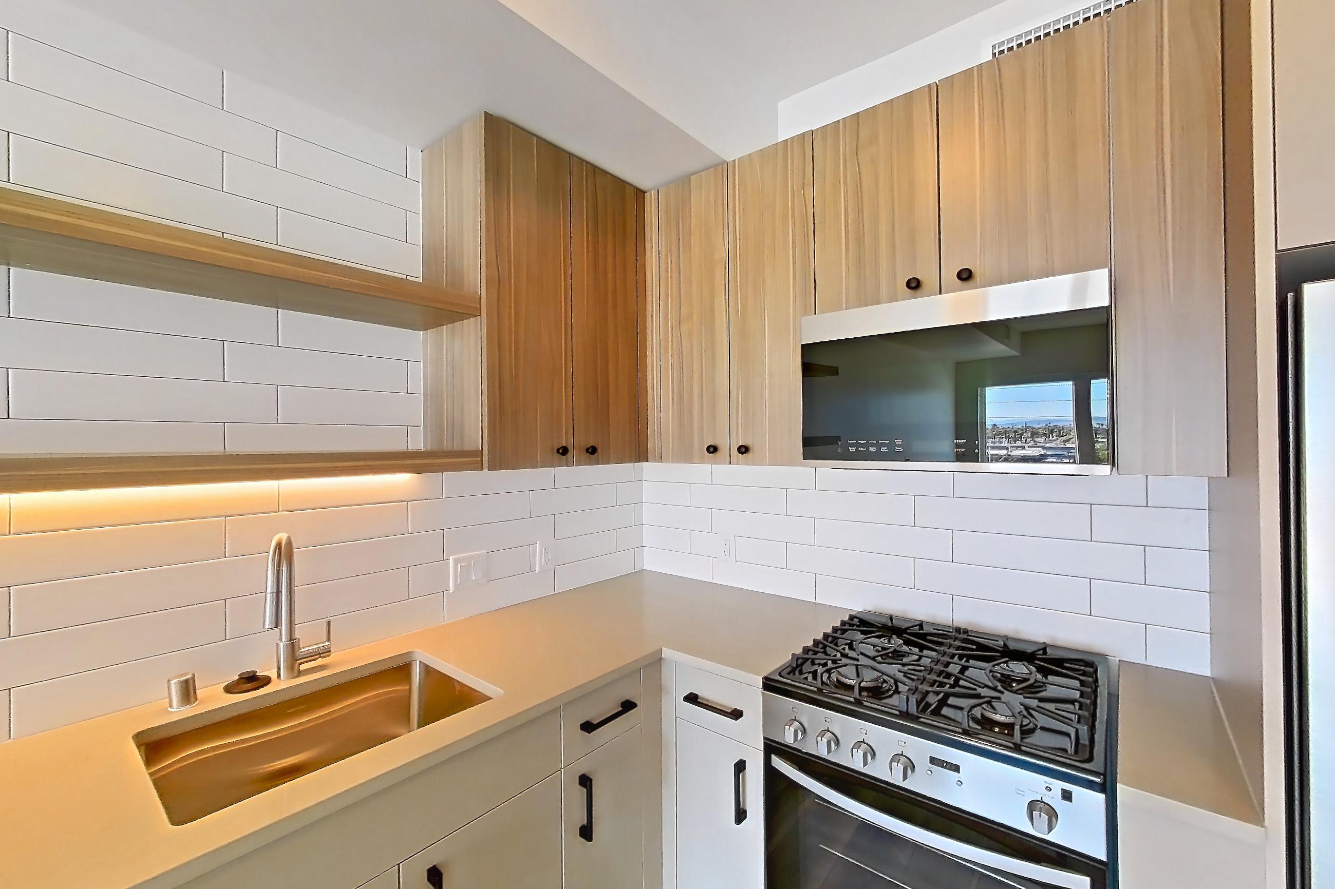 Kitchen with dishwasher, gas range, light countertops, light wood-finish flooring, oven/range, refrigerator, and stainless steel appliances, Apartment 526 at The Myles