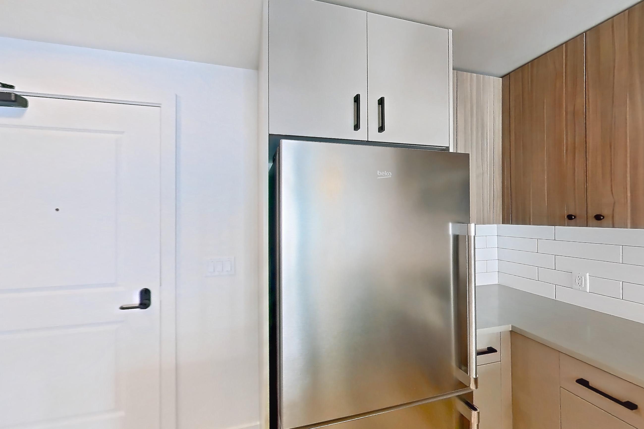 Kitchen with dishwasher, gas range, light countertops, light wood-finish flooring, oven/range, refrigerator, and stainless steel appliances, Apartment 527 at The Myles