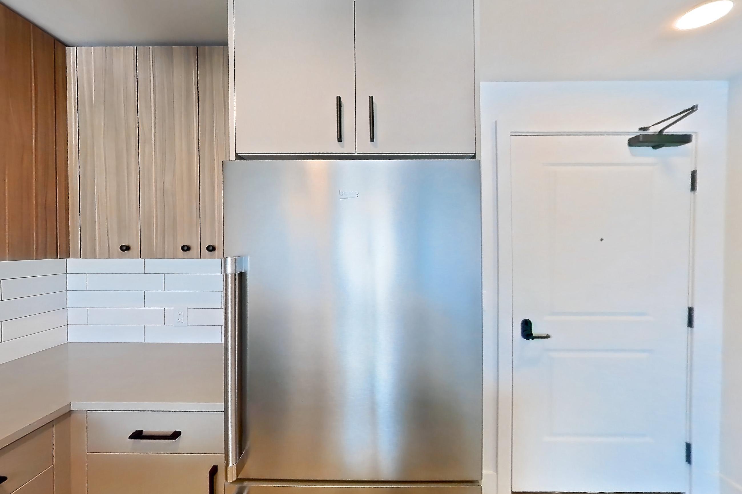 Kitchen with dishwasher, gas range, light countertops, light wood-finish flooring, microwave, oven/range, refrigerator, and stainless steel appliances, Apartment 550 at The Myles