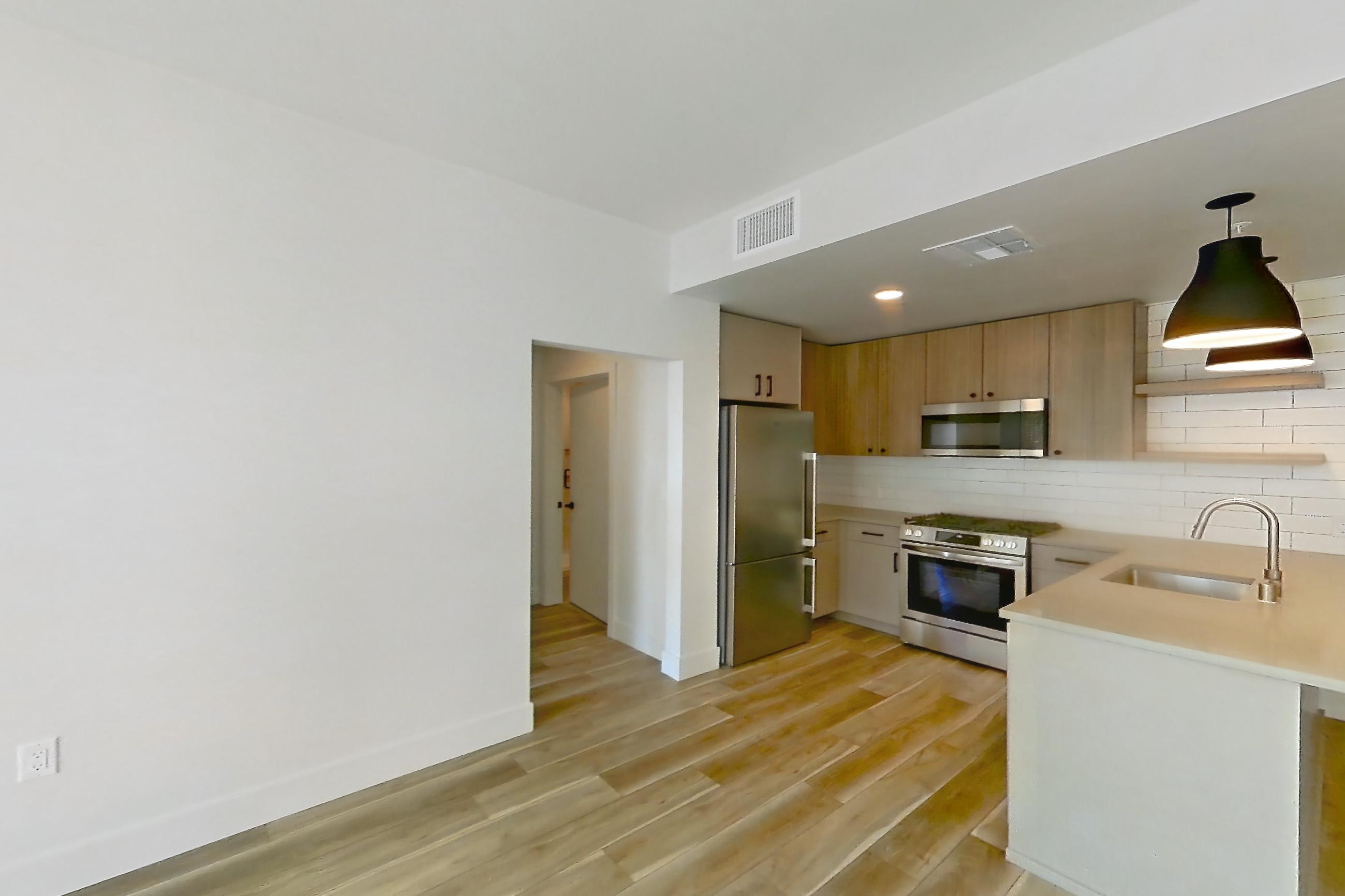 Living room with light wood-finish flooring, refrigerator, stainless steel appliances, and wood-look tile flooring, Apartment 554 at The Myles