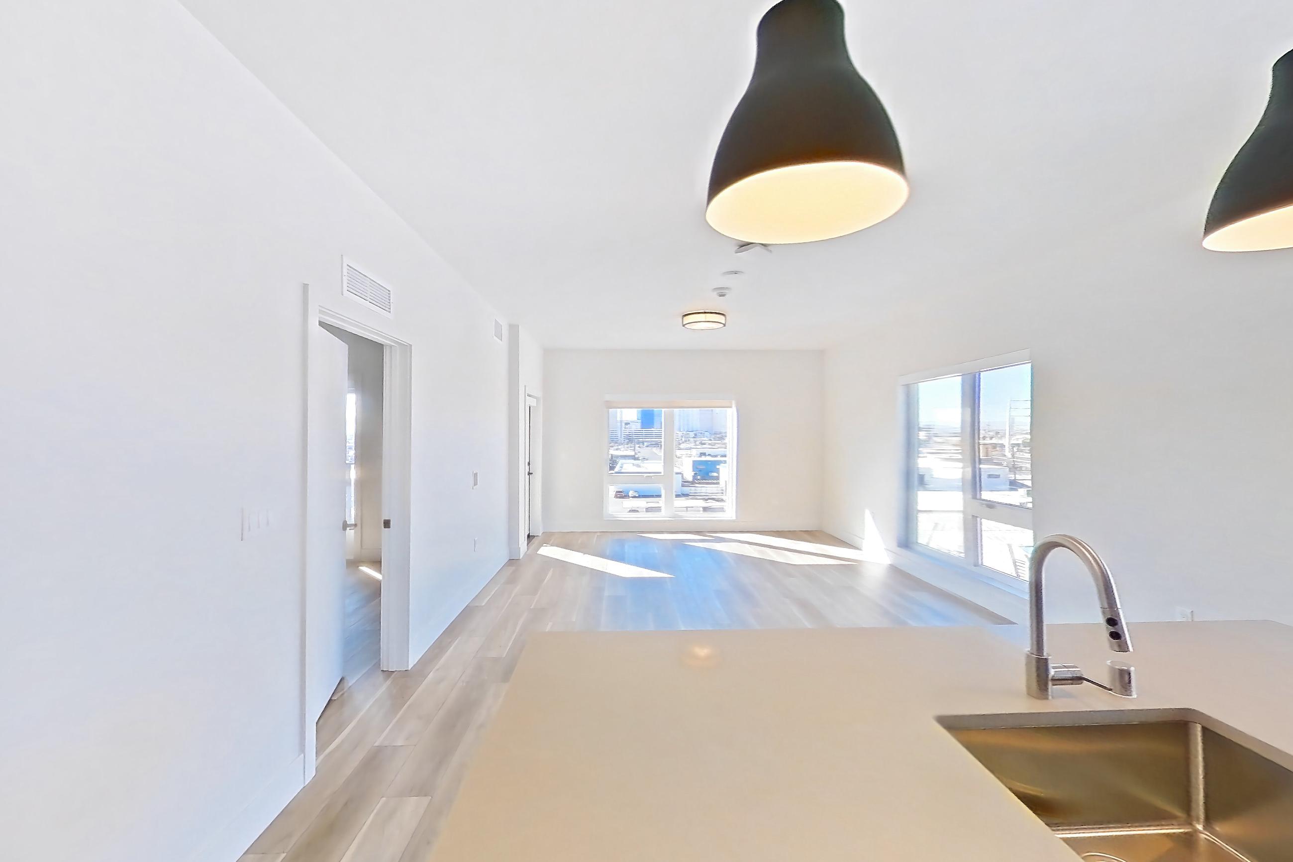 Kitchen with dishwasher, gas range, kitchen island, light countertops, light stone countertops, light wood-finish flooring, microwave, oven/range, refrigerator, stainless steel appliances, and wood-look tile flooring, Apartment 556 at The Myles