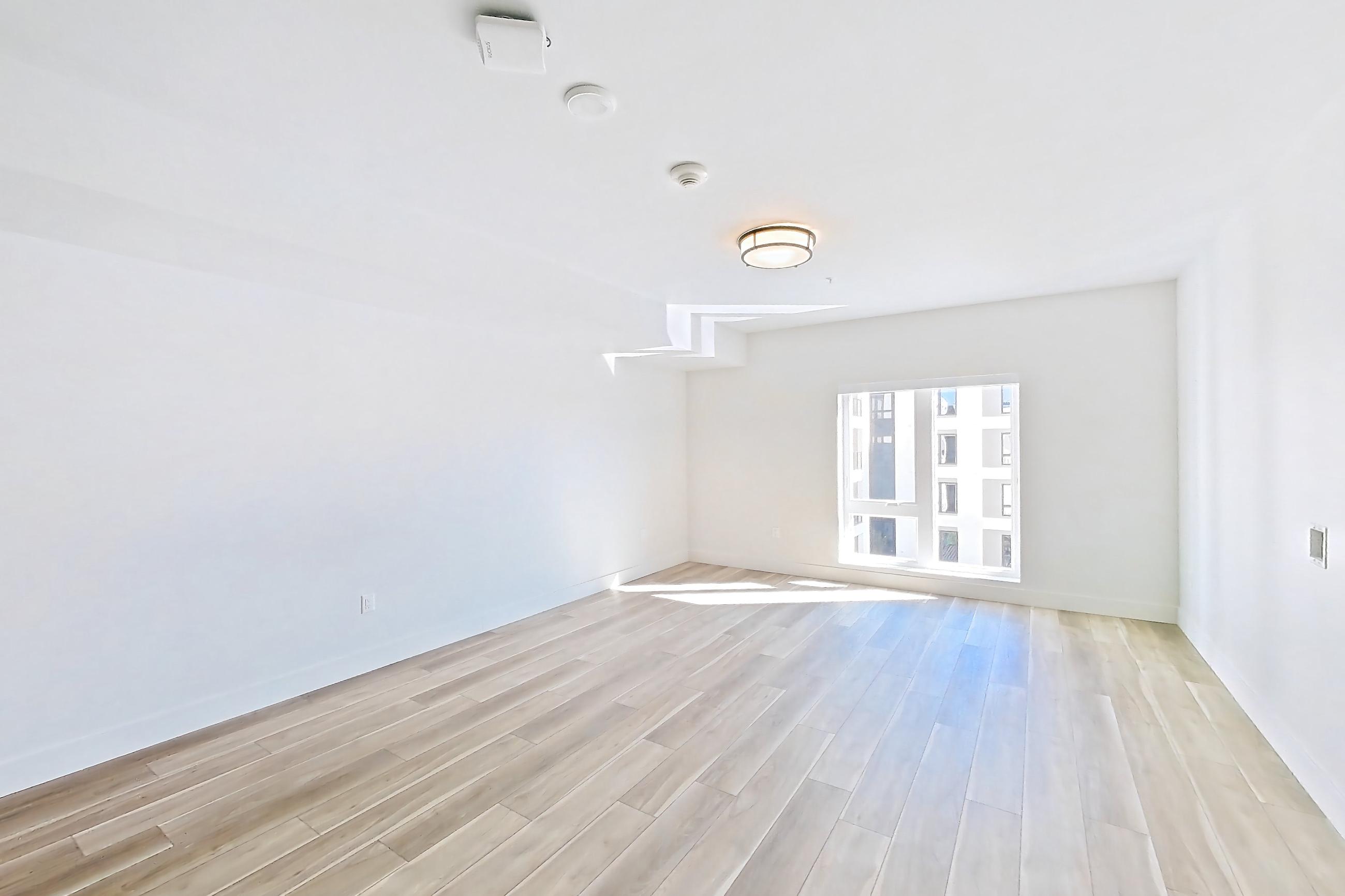 Living room with gas range, light countertops, light wood-finish flooring, oven/range, refrigerator, and stainless steel appliances, Apartment 603 at The Myles