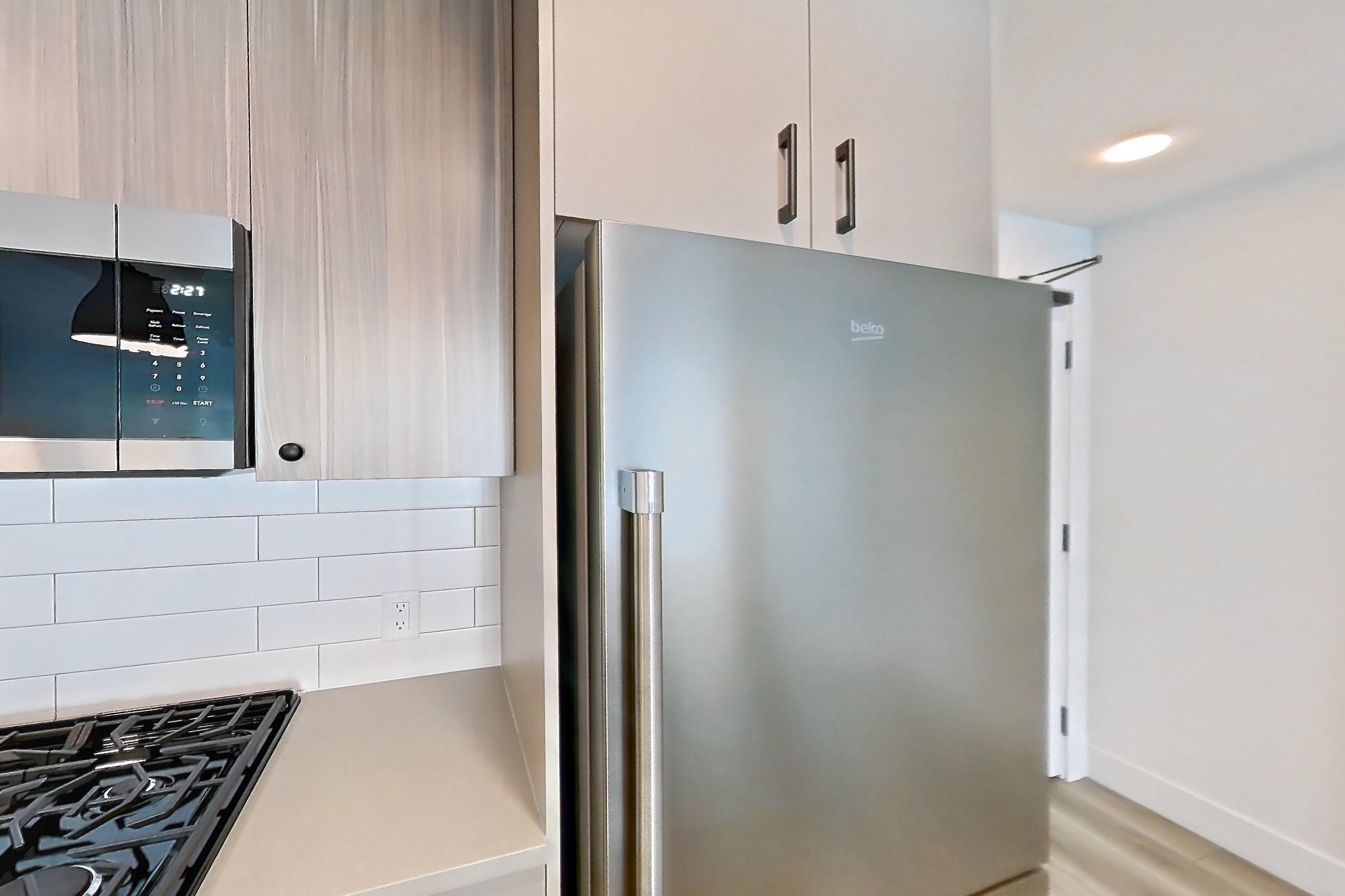 Kitchen with dishwasher, gas range, light countertops, light wood-finish flooring, microwave, oven/range, and stainless steel appliances, Apartment 604 at The Myles