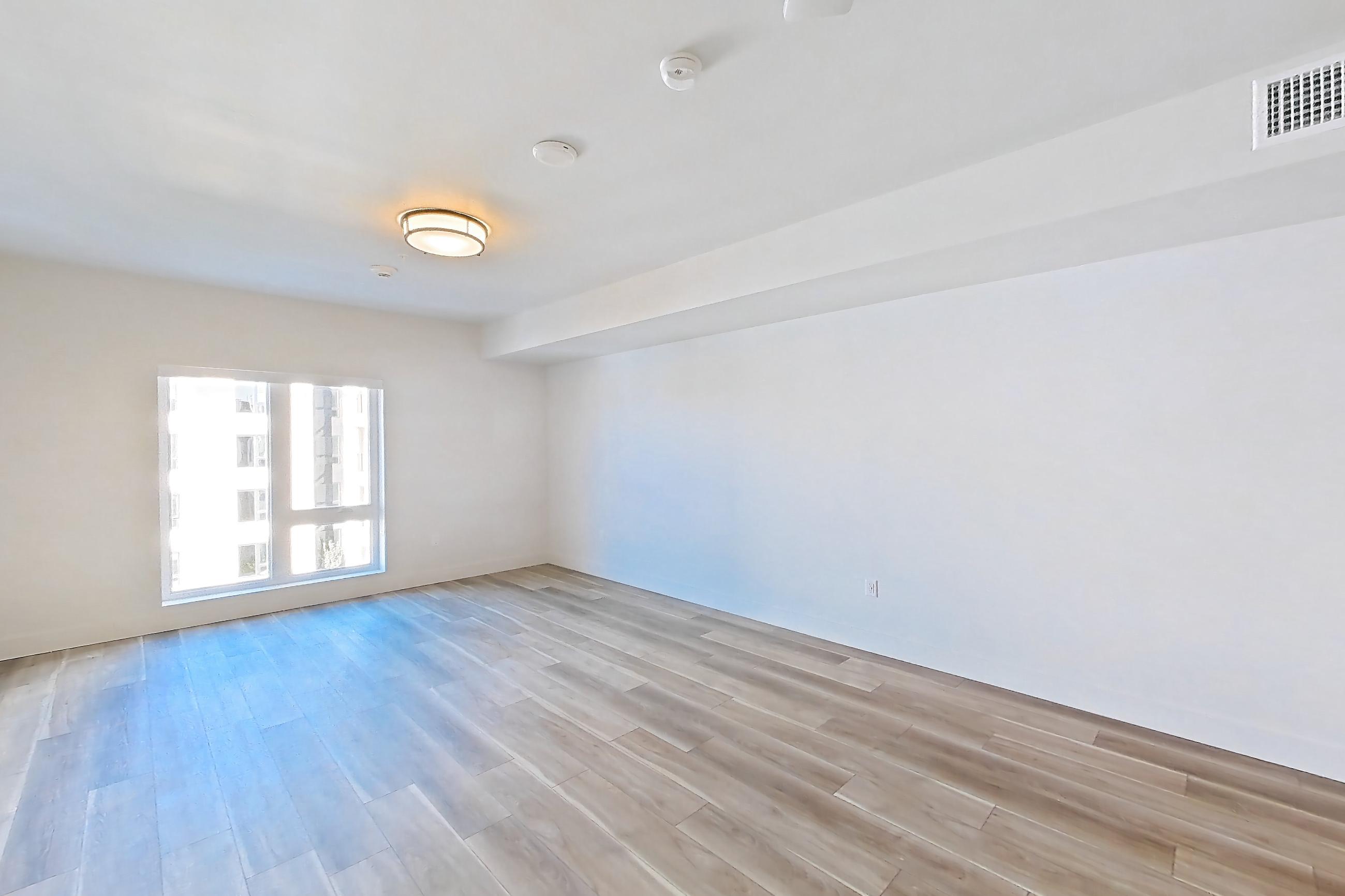 Living room with gas range, light countertops, light wood-finish flooring, refrigerator, and stainless steel appliances, Apartment 604 at The Myles