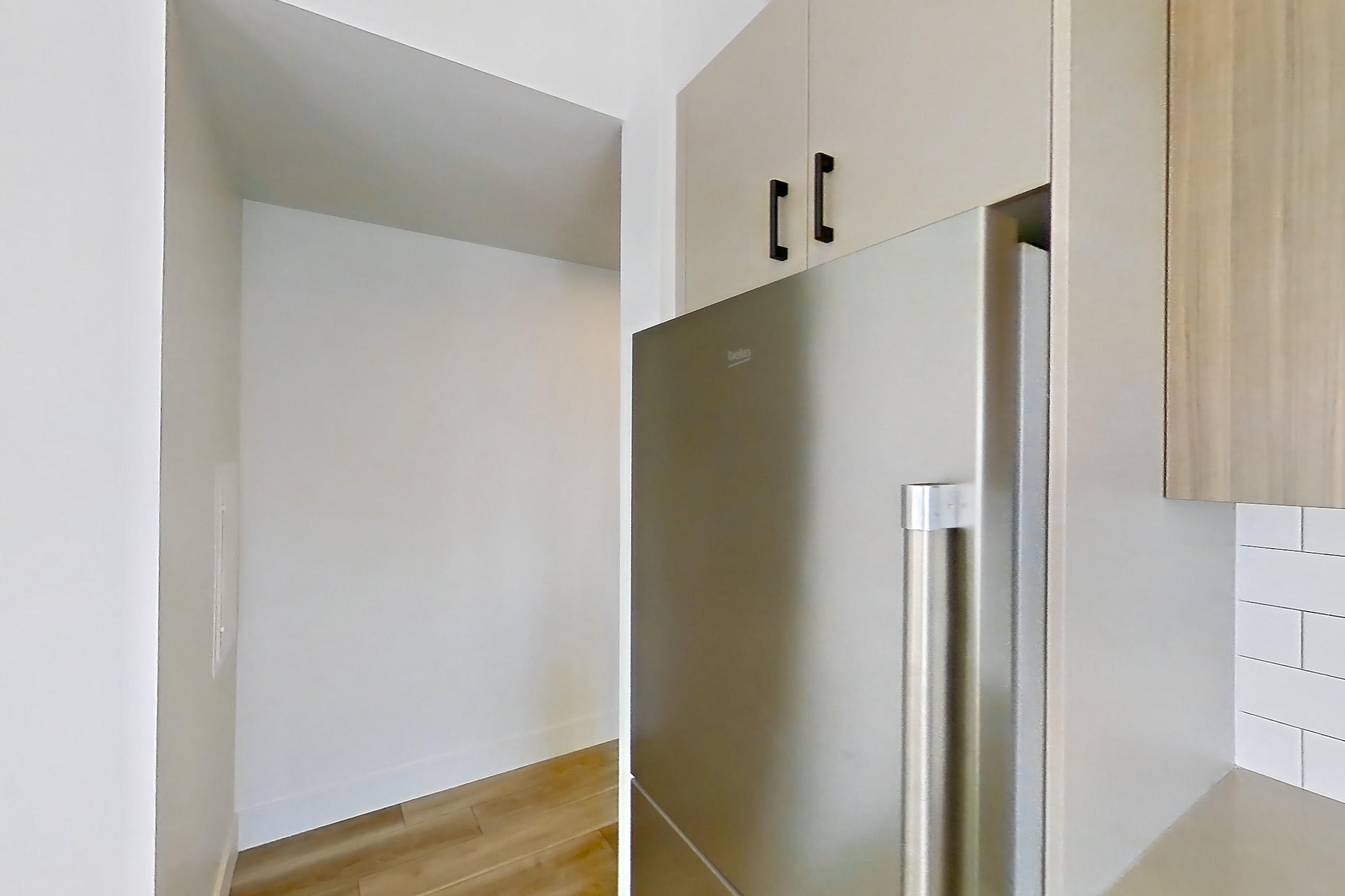 Kitchen with dishwasher, gas range, kitchen island, light countertops, light stone countertops, light wood-finish flooring, microwave, oven/range, and stainless steel appliances, Apartment 605 at The Myles