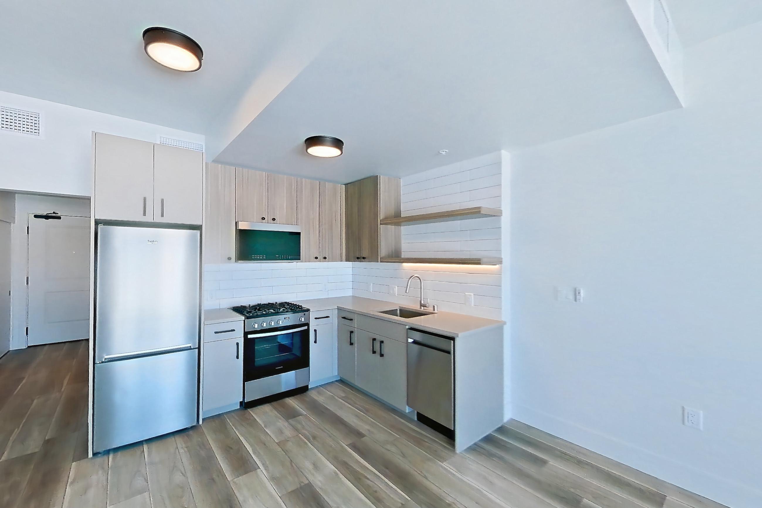 Living space with dishwasher, gas range, light stone countertops, light wood-finish flooring, oven/range, and stainless steel appliances, Apartment 608 at The Myles