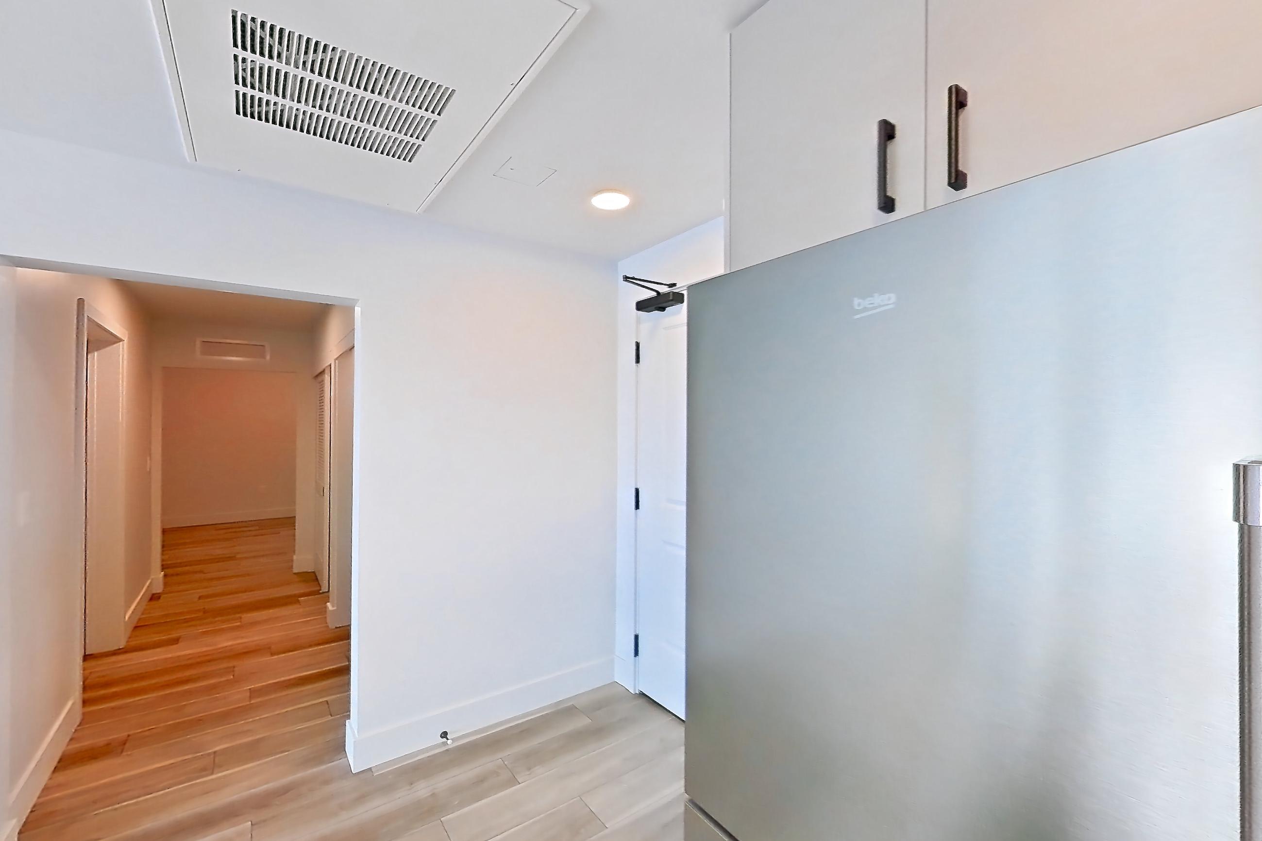 Kitchen with gas range, light countertops, light wood-finish flooring, microwave, oven/range, refrigerator, stainless steel appliances, and wood-look tile flooring, Apartment 611 at The Myles