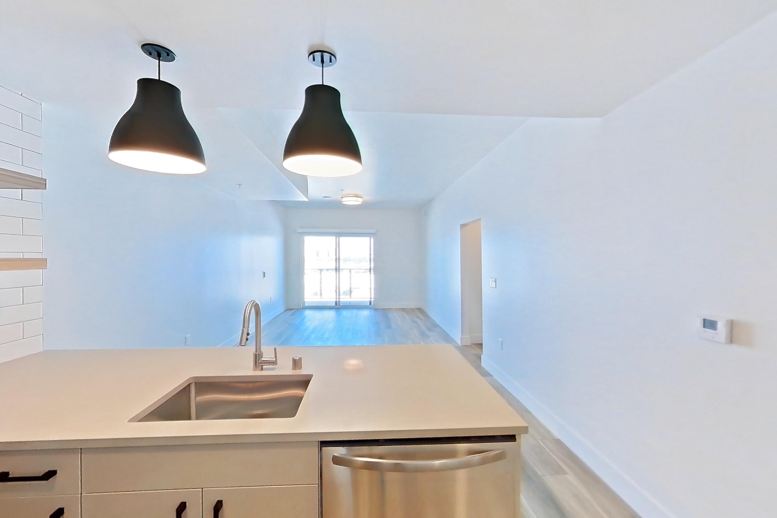 Kitchen with dishwasher, gas range, light countertops, light wood-finish flooring, microwave, oven/range, refrigerator, and stainless steel appliances, Apartment 612 at The Myles