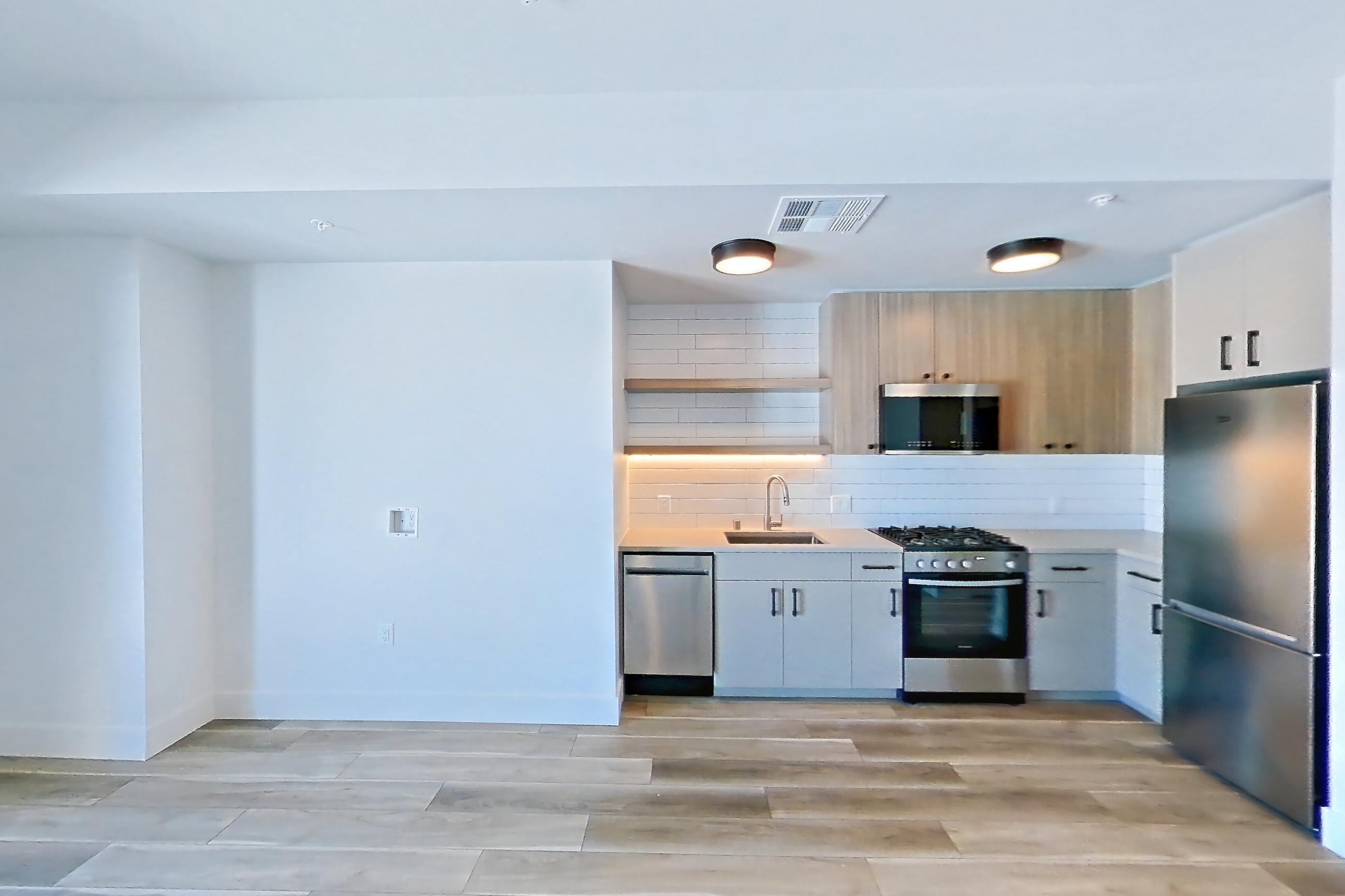 Living space with dishwasher, gas range, light countertops, light wood-finish flooring, microwave, oven/range, refrigerator, and stainless steel appliances, Apartment 620 at The Myles