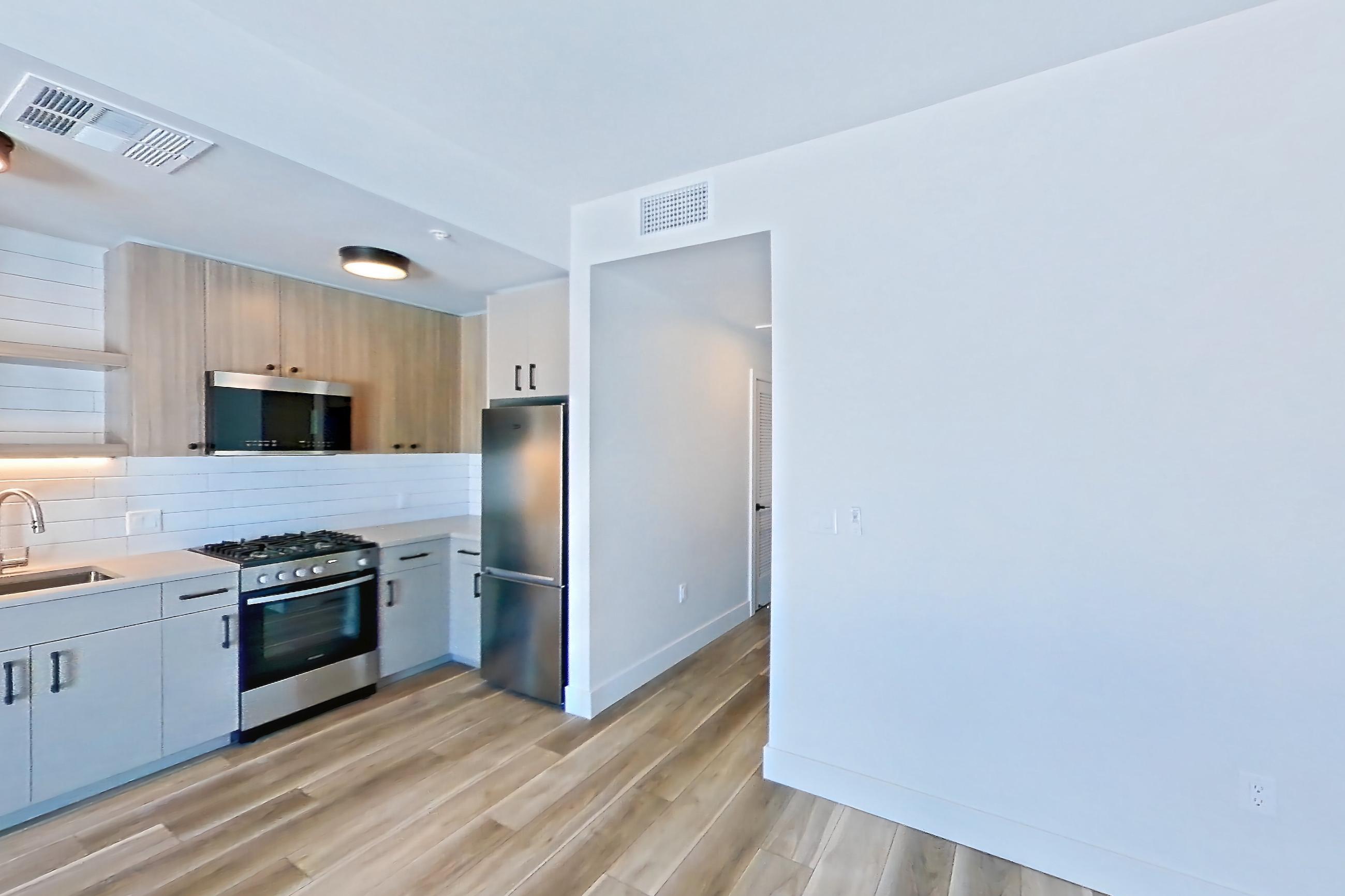 Living space with dishwasher, gas range, light countertops, light wood-finish flooring, microwave, oven/range, refrigerator, and stainless steel appliances, Apartment 620 at The Myles