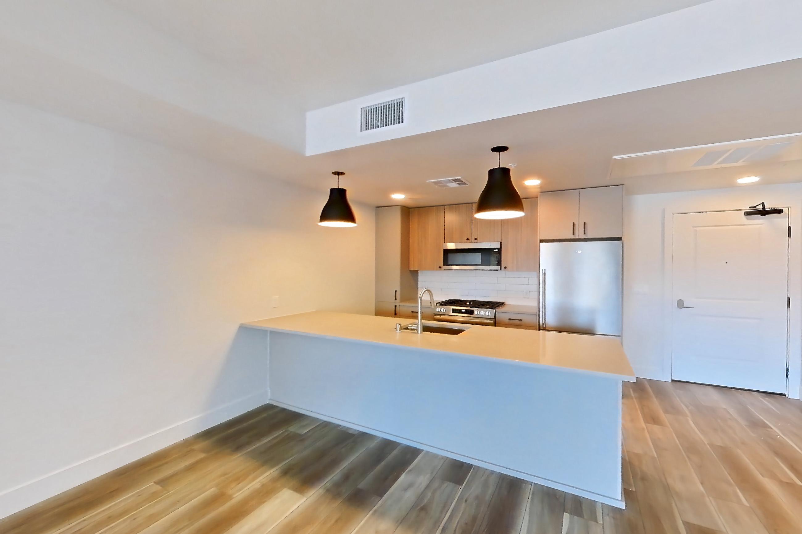 Living room with light countertops and light wood-finish flooring, Apartment 621 at The Myles