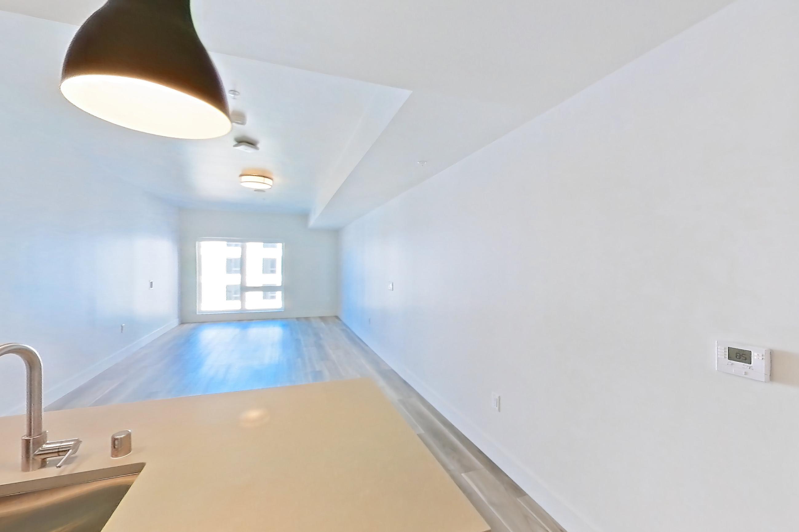 Kitchen with dishwasher, gas range, kitchen island, light countertops, light wood-finish flooring, microwave, oven/range, refrigerator, and stainless steel appliances, Apartment 627 at The Myles