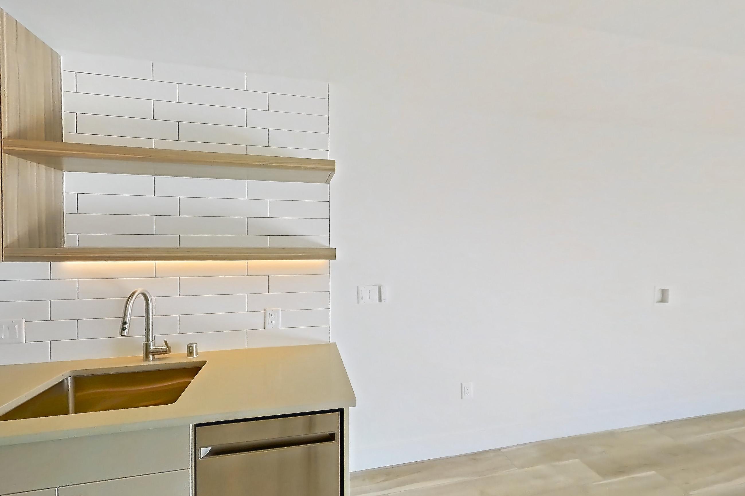 Kitchen with dishwasher, gas range, light countertops, light wood-finish flooring, oven/range, and stainless steel appliances, Apartment 628 at The Myles