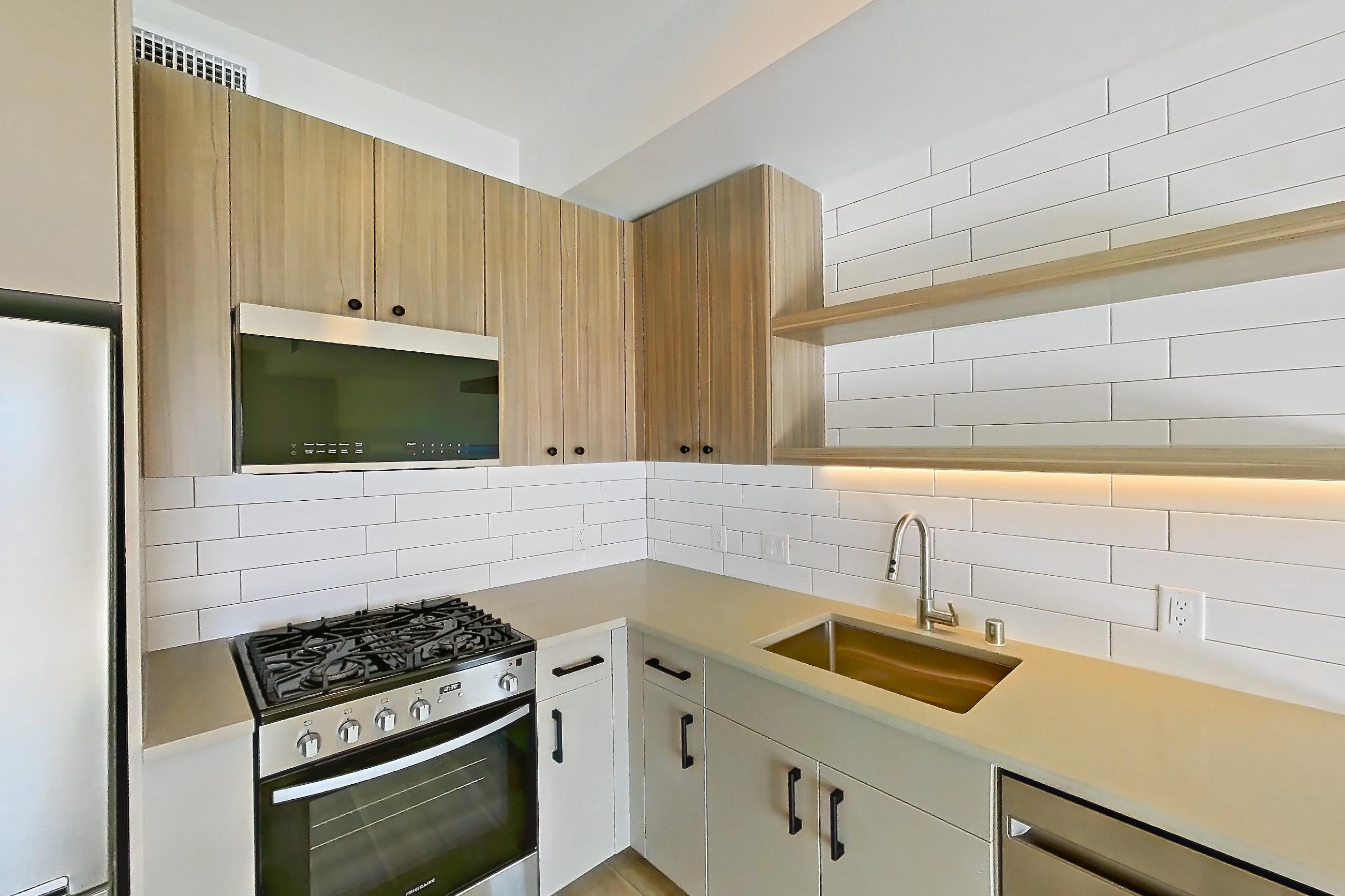 Kitchen with dishwasher, gas range, light countertops, light wood-finish flooring, oven/range, and stainless steel appliances, Apartment 628 at The Myles