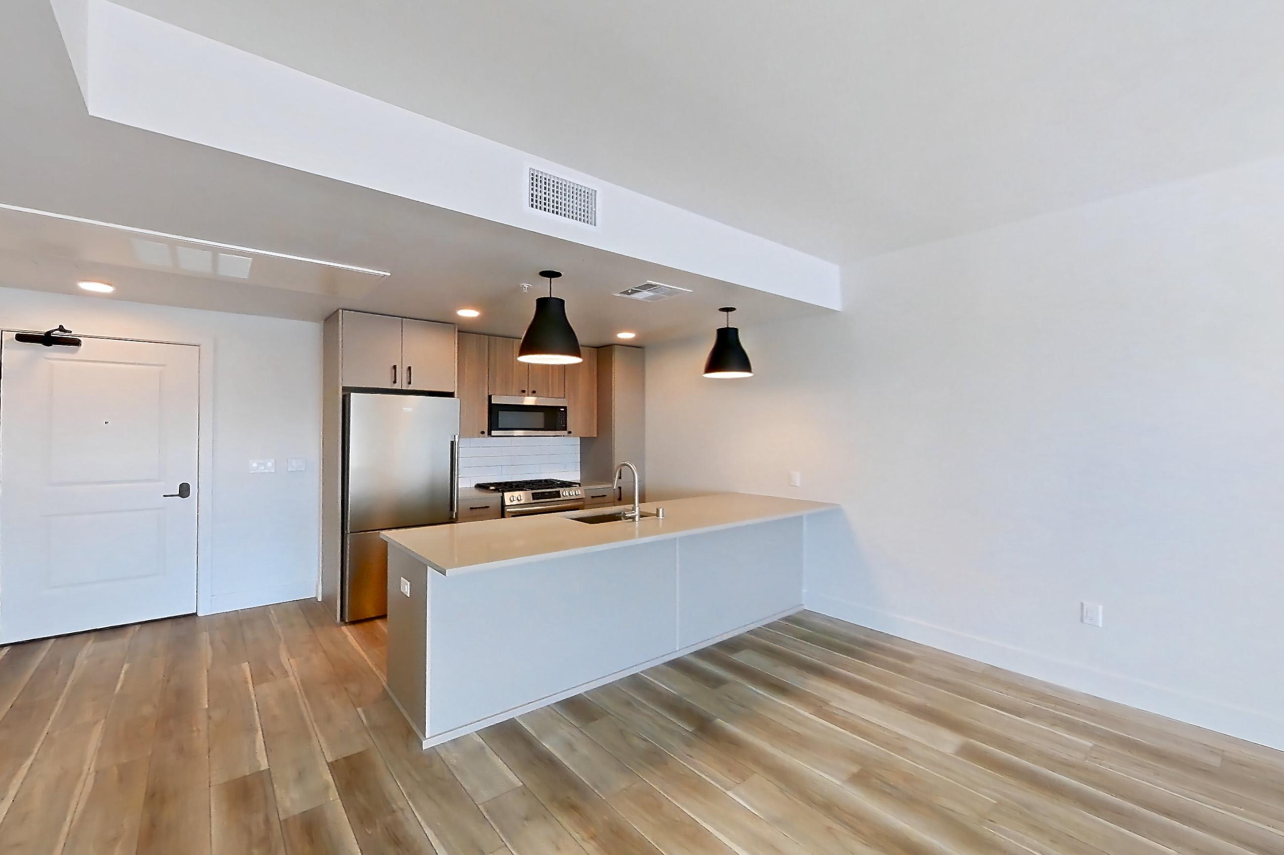 Living room with gas range, light countertops, light wood-finish flooring, oven/range, and stainless steel appliances, Apartment 630 at The Myles