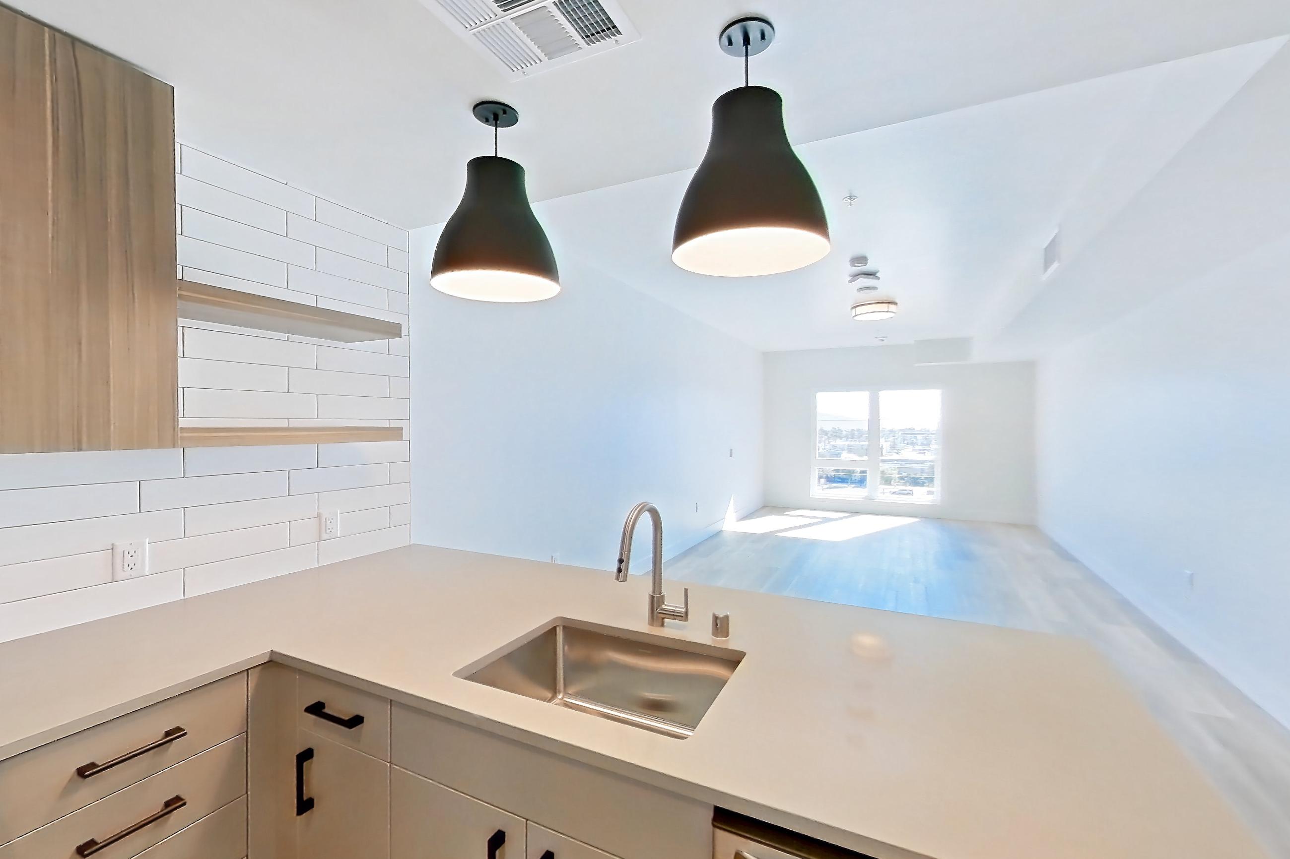 Kitchen with dishwasher, gas range, light countertops, light wood-finish flooring, oven/range, refrigerator, and stainless steel appliances, Apartment 625 at The Myles