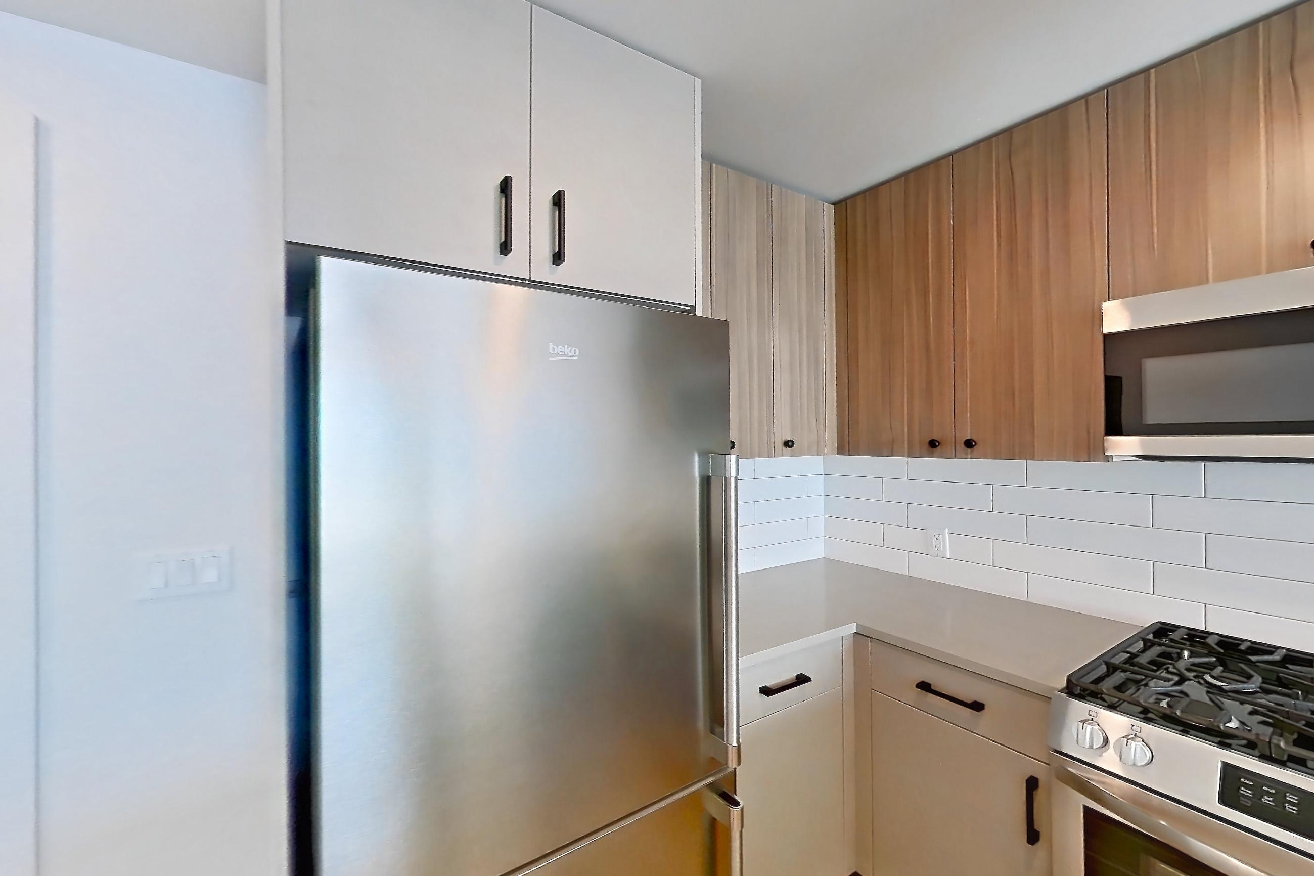 Kitchen with dishwasher, gas range, light countertops, light wood-finish flooring, oven/range, refrigerator, and stainless steel appliances, Apartment 625 at The Myles