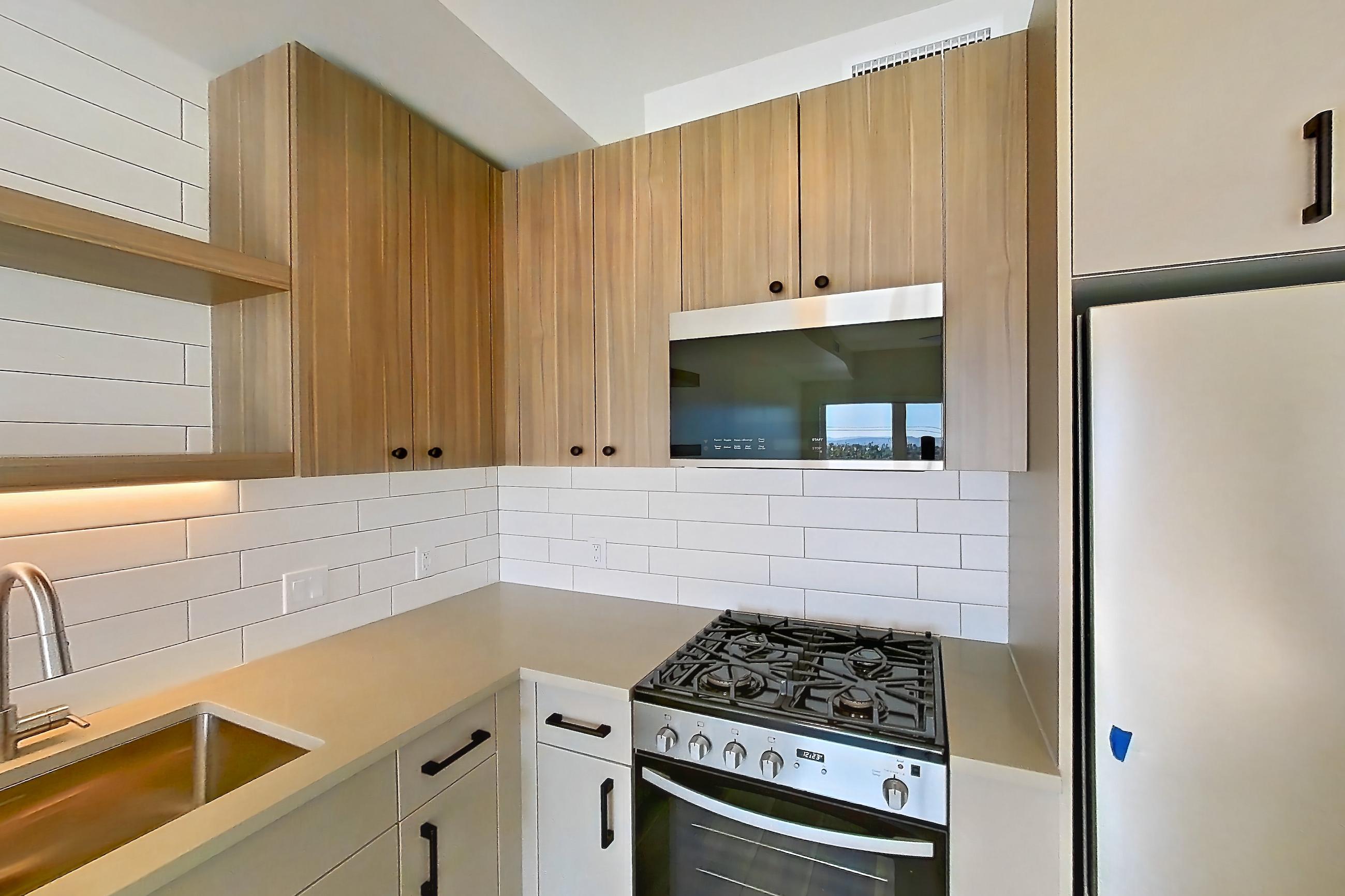 Kitchen with gas range, light countertops, light wood-finish flooring, oven/range, and stainless steel appliances, Apartment 626 at The Myles