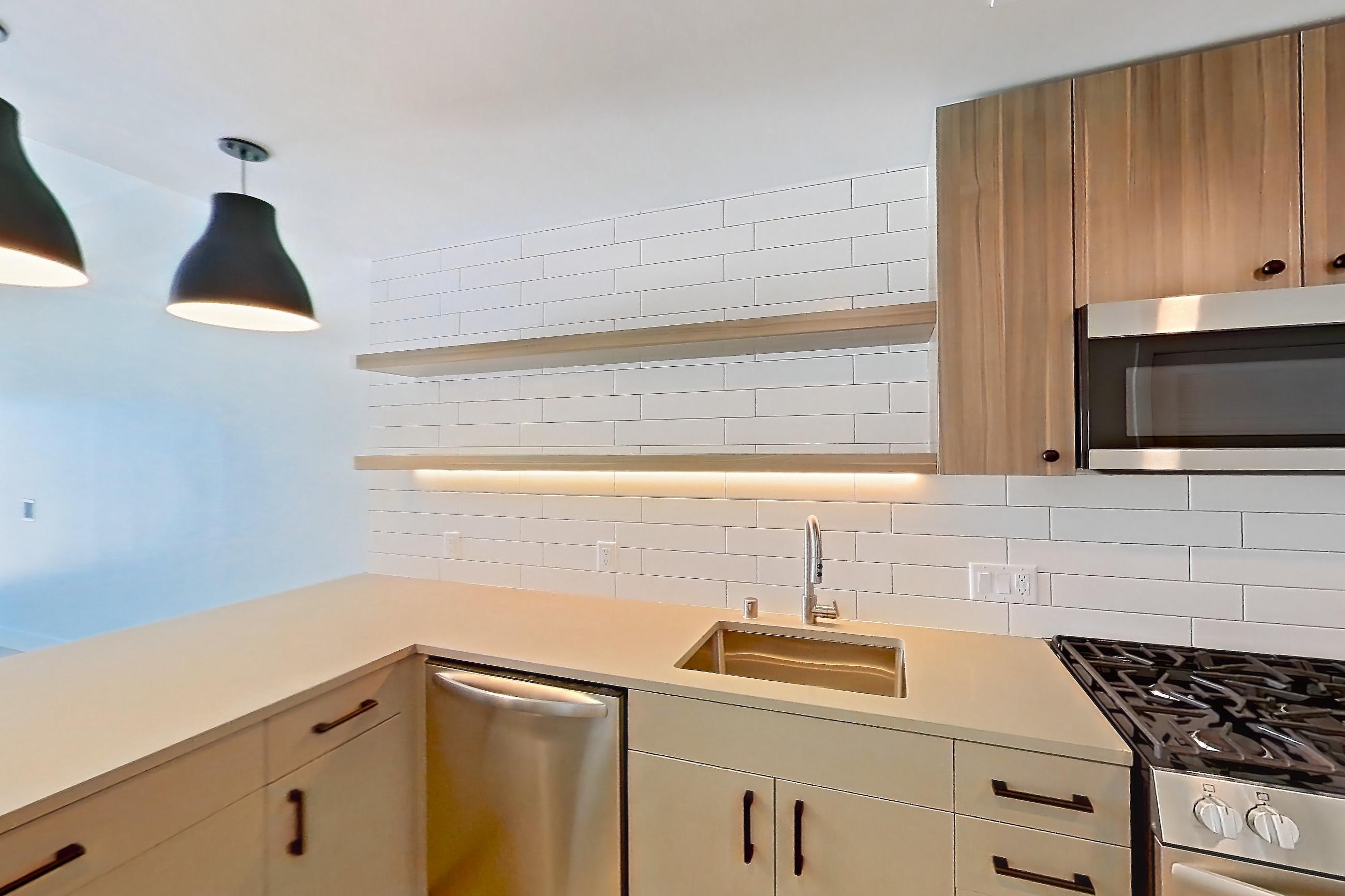 Kitchen with dishwasher, gas range, light countertops, light wood-finish flooring, microwave, oven/range, refrigerator, and stainless steel appliances, Apartment 634 at The Myles