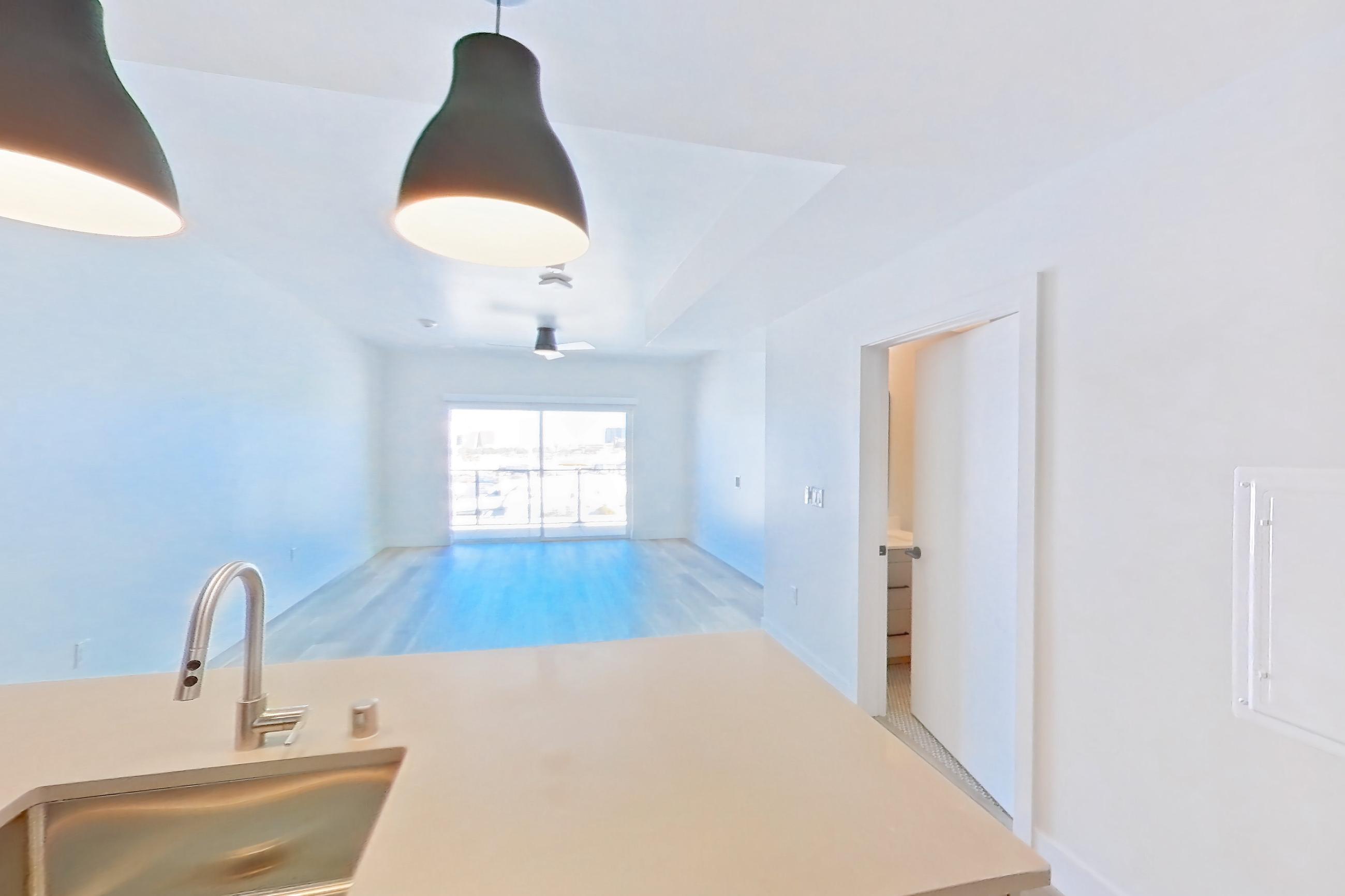 Kitchen with dishwasher, gas range, light countertops, light wood-finish flooring, oven/range, refrigerator, and stainless steel appliances, Apartment 635 at The Myles